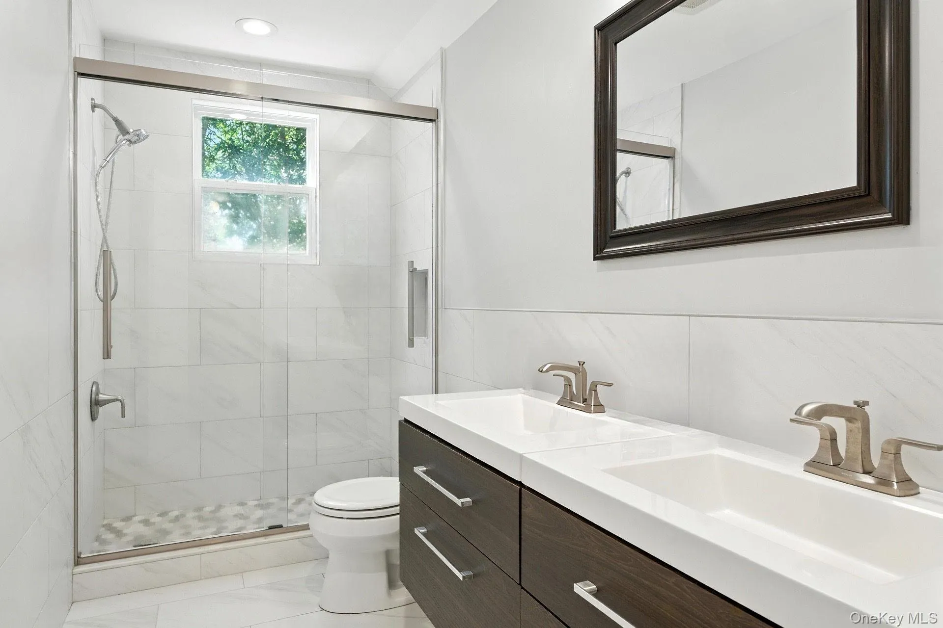 Full bathroom featuring double vanity, tile walls, and a stall shower. Full bathroom featuring double vanity, tile walls, and a stall shower.
