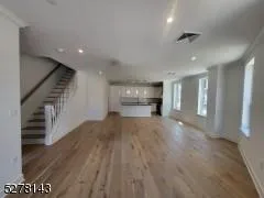 Unfurnished living room with wood finished floors, recessed lighting, and stairs Unfurnished living room with wood finished floors, recessed lighting, and stairs