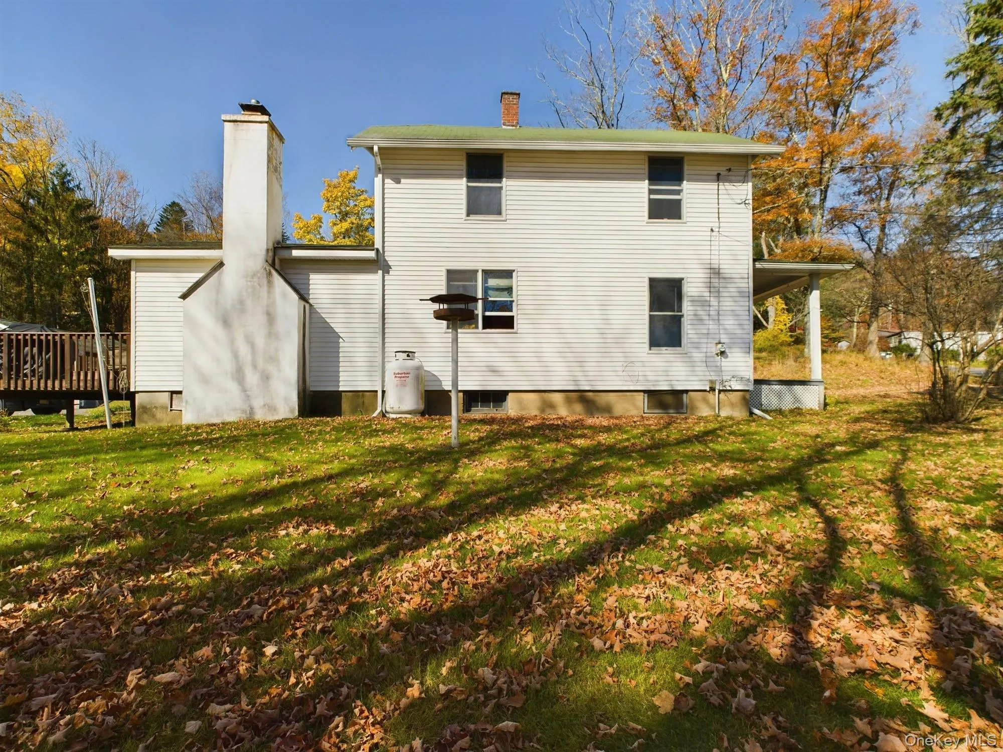 Back of house with a chimney, a lawn, and a deck Back of house with a chimney, a lawn, and a deck