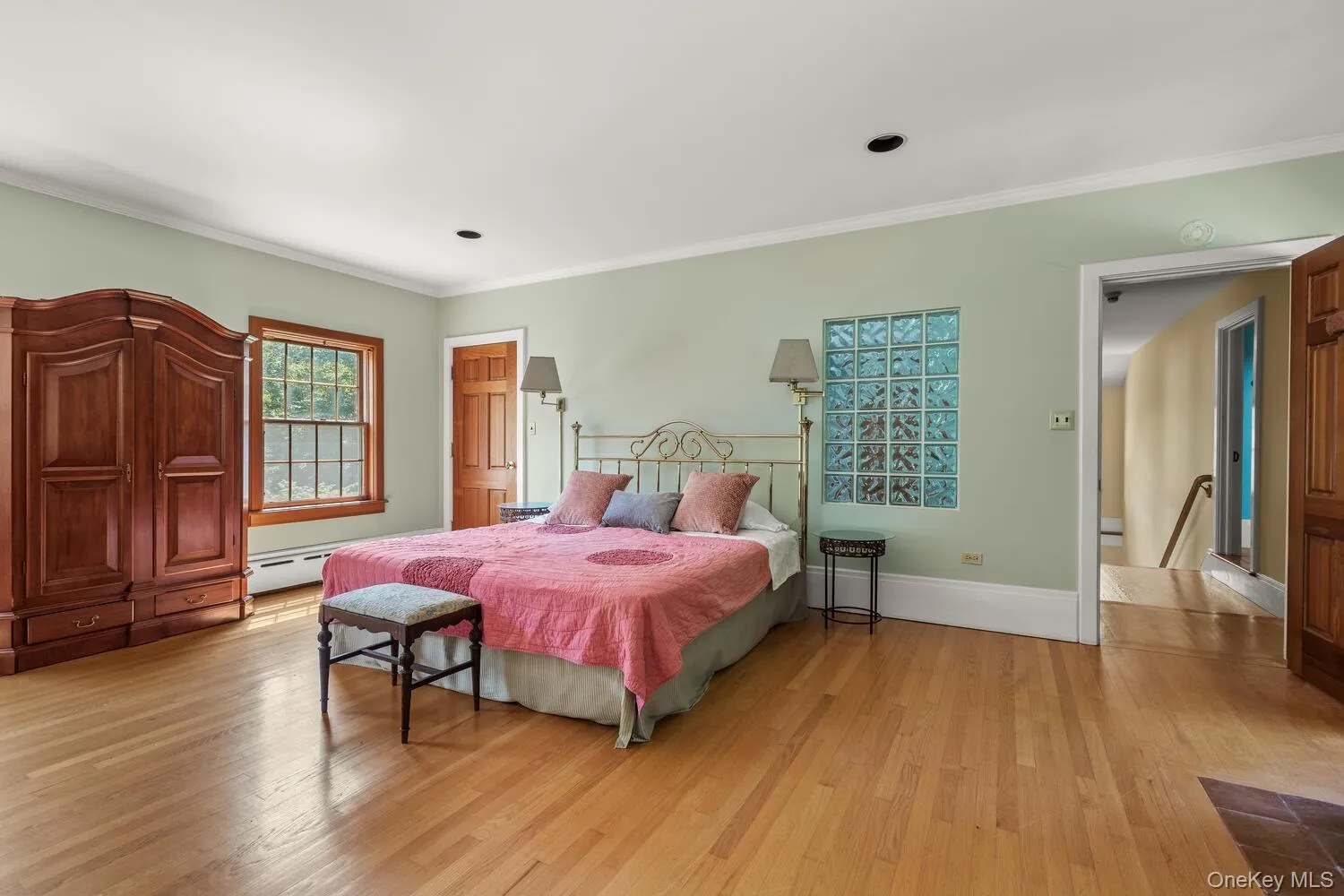 Bedroom featuring light wood-style floors, crown molding, and a baseboard radiator Bedroom featuring light wood-style floors, crown molding, and a baseboard radiator