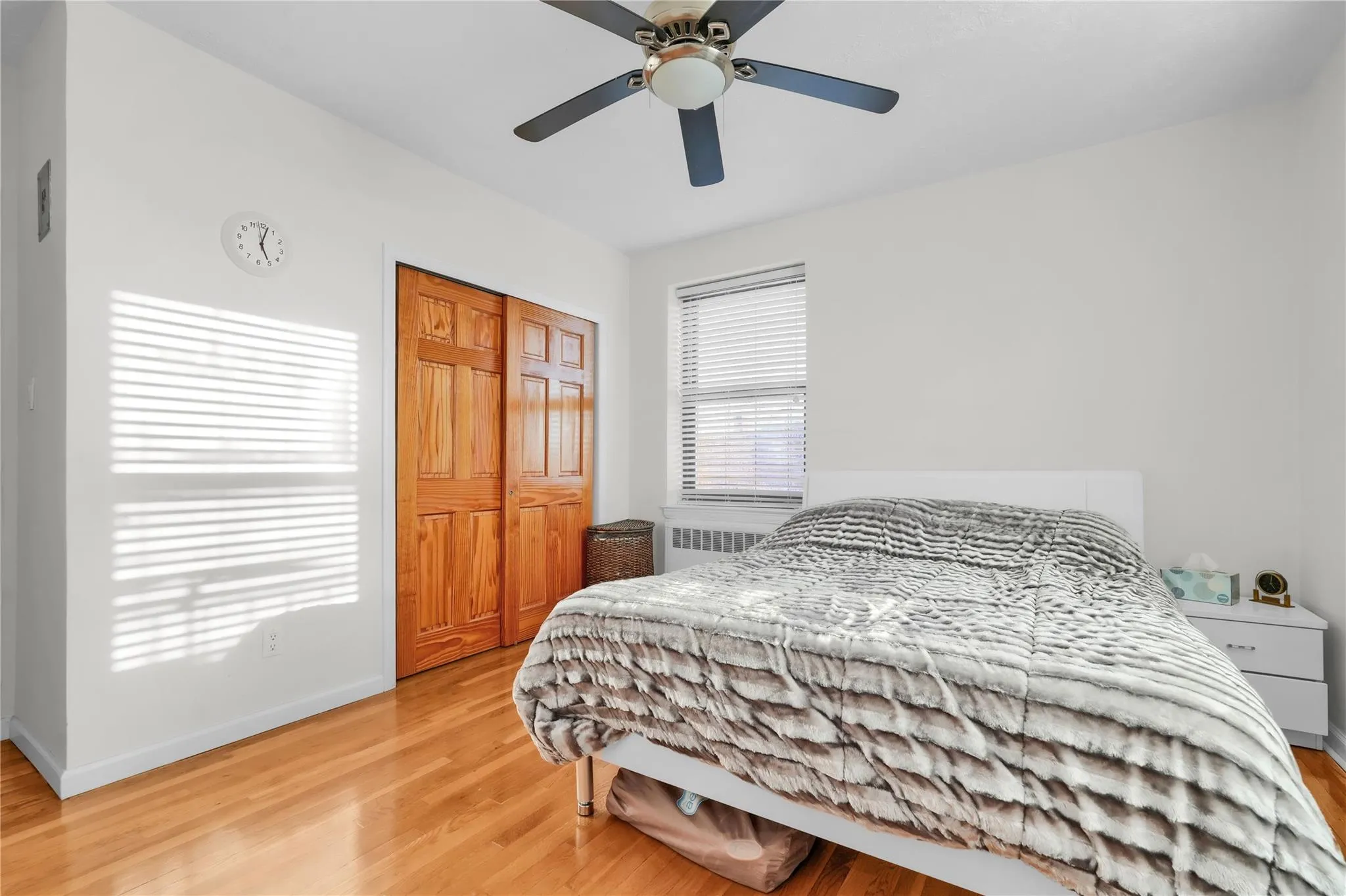 Bedroom with light wood-type flooring, radiator, and ceiling fan Bedroom with light wood-type flooring, radiator, and ceiling fan