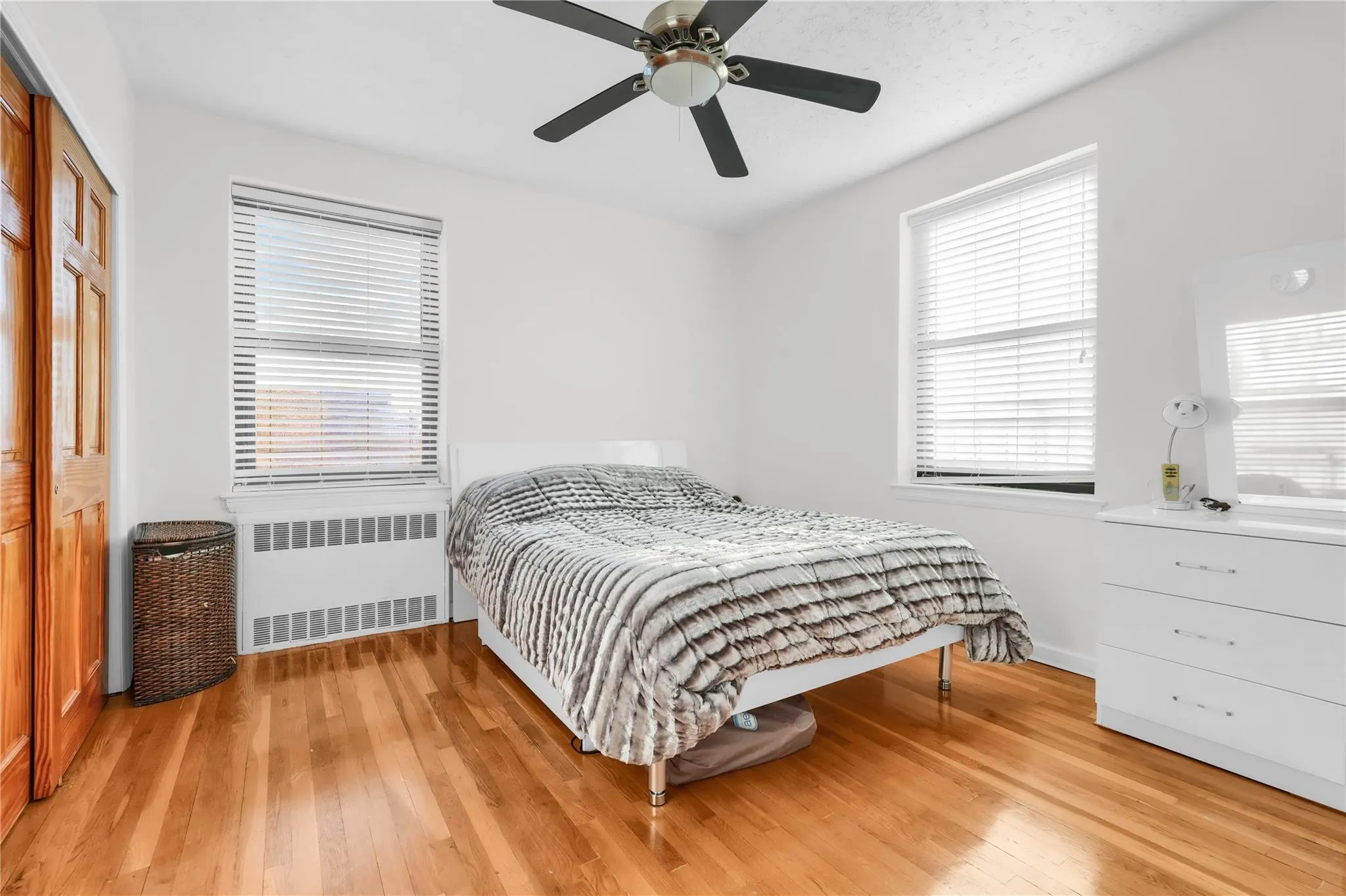 Bedroom with radiator, hardwood / wood-style floors, a ceiling fan, and a closet Bedroom with radiator, hardwood / wood-style floors, a ceiling fan, and a closet