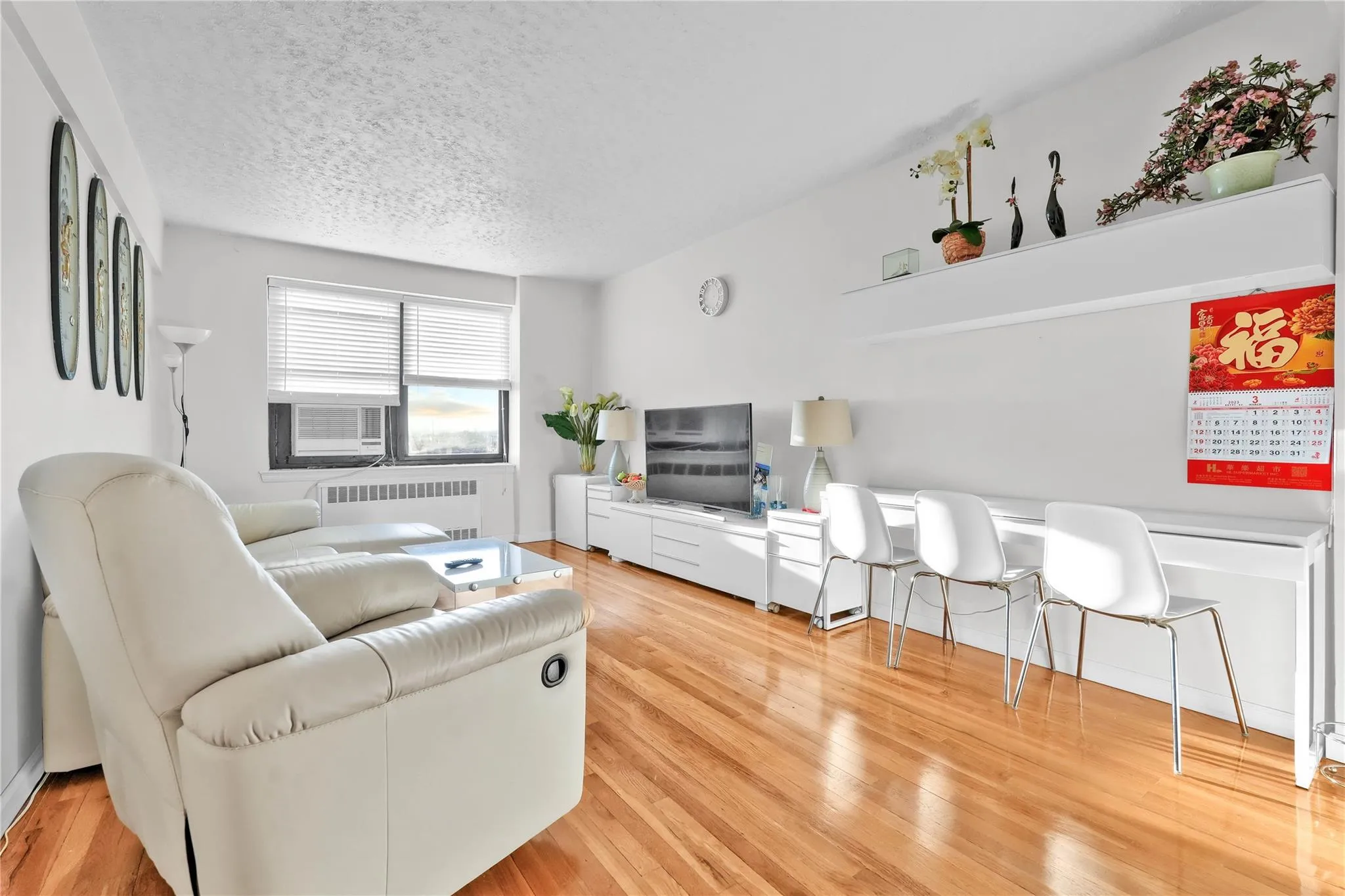 Living room featuring radiator, light wood-type flooring, a textured ceiling, and cooling unit Living room featuring radiator, light wood-type flooring, a textured ceiling, and cooling unit