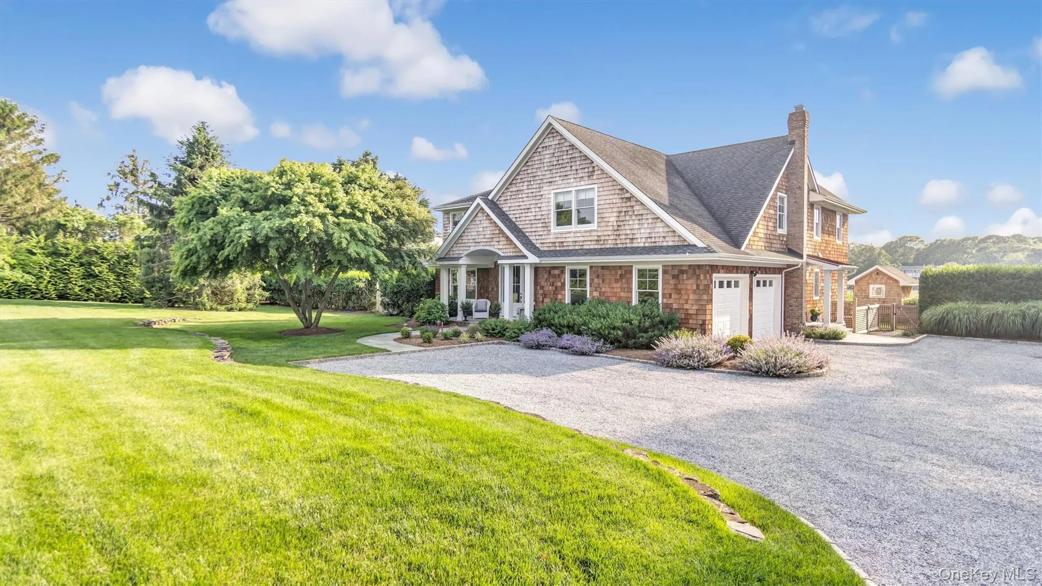 Shingle-style home featuring driveway, a chimney, a front lawn, and roof with shingles Shingle-style home featuring driveway, a chimney, a front lawn, and roof with shingles