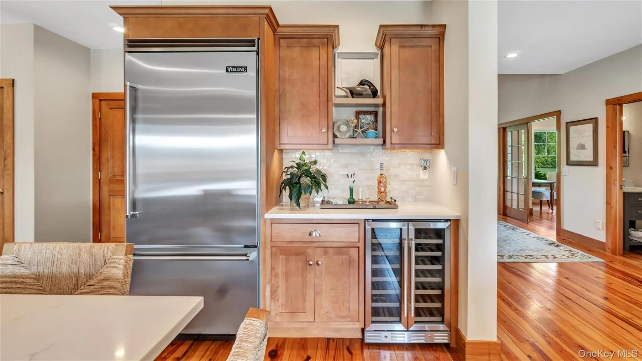 Kitchen with built in fridge, beverage cooler, hardwood / wood-style flooring, light countertops, and decorative backsplash Kitchen with built in fridge, beverage cooler, hardwood / wood-style flooring, light countertops, and decorative backsplash