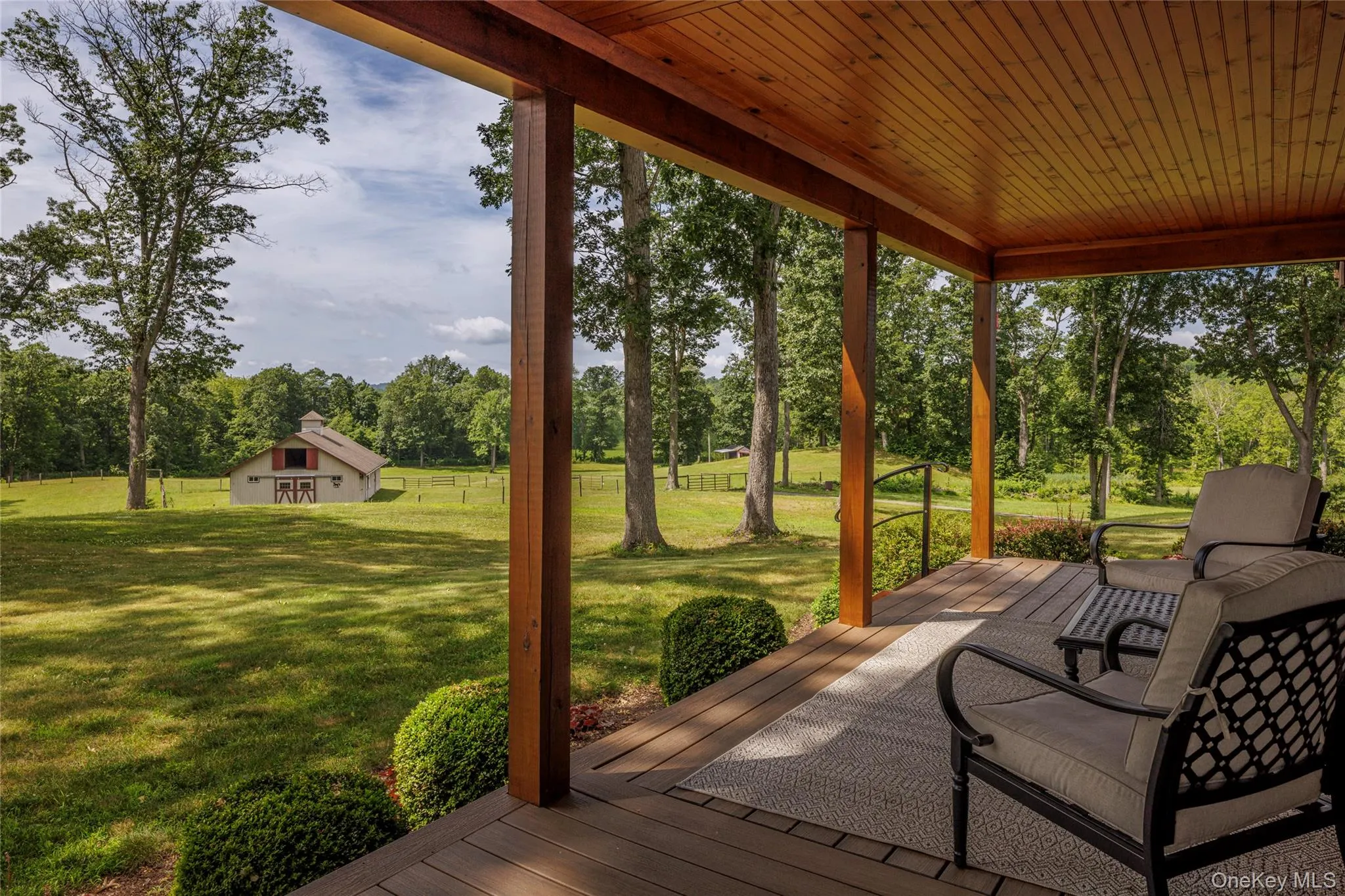 Wooden terrace with an outbuilding, a yard, and view of scattered trees Wooden terrace with an outbuilding, a yard, and view of scattered trees