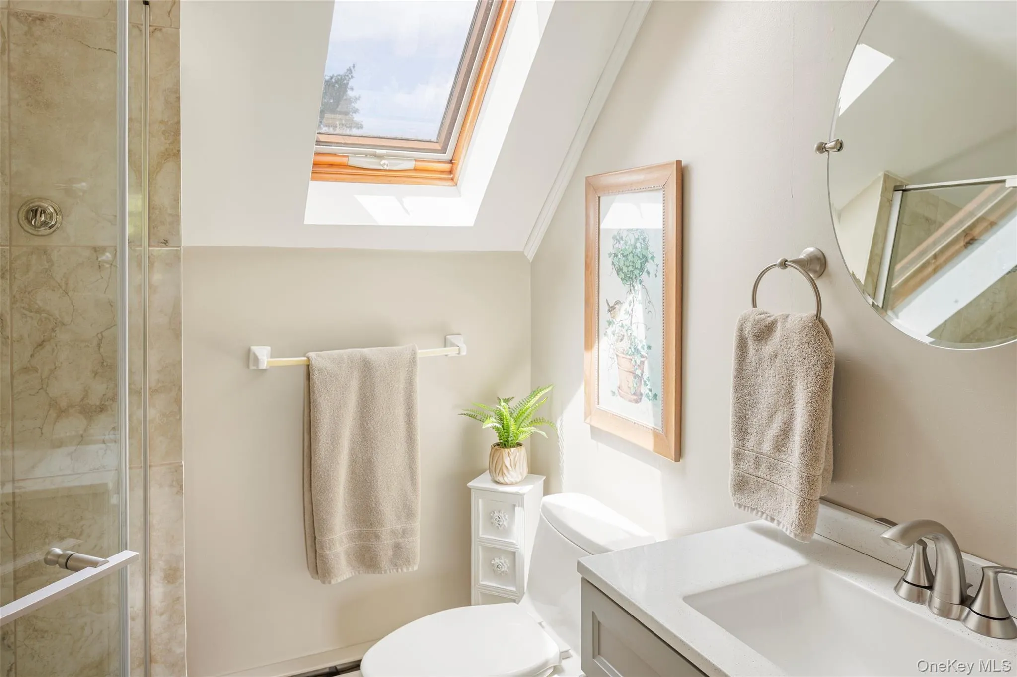 Full bath featuring a skylight, healthy amount of natural light, vanity, and a tile shower Full bath featuring a skylight, healthy amount of natural light, vanity, and a tile shower