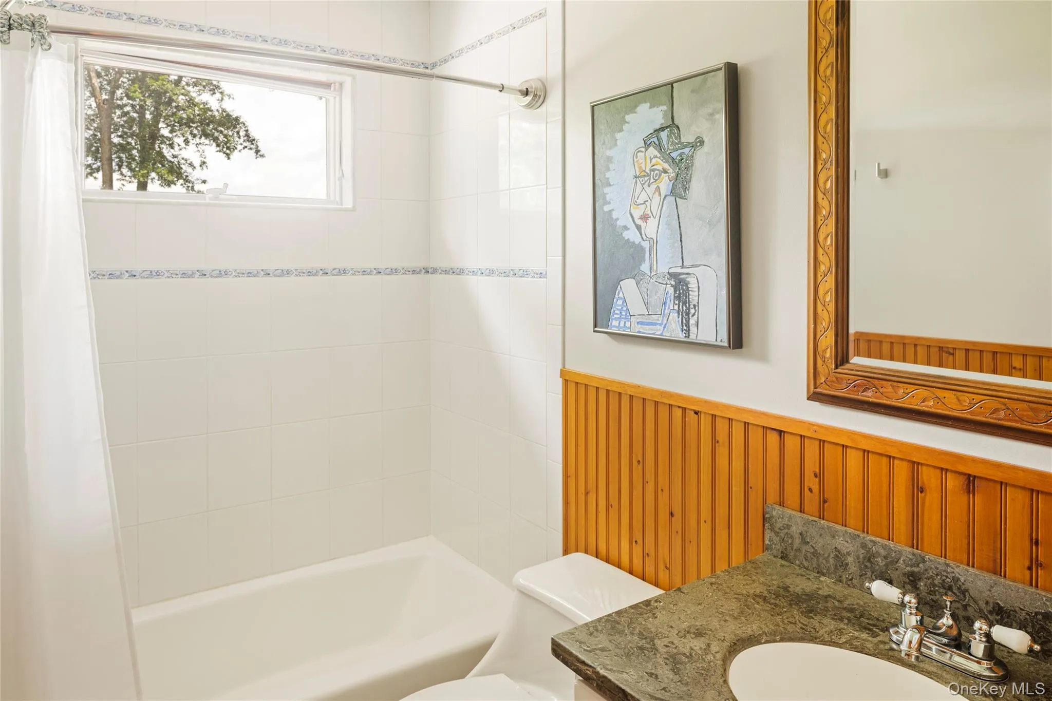 Bathroom featuring vanity, wainscoting, and shower / tub combo Bathroom featuring vanity, wainscoting, and shower / tub combo