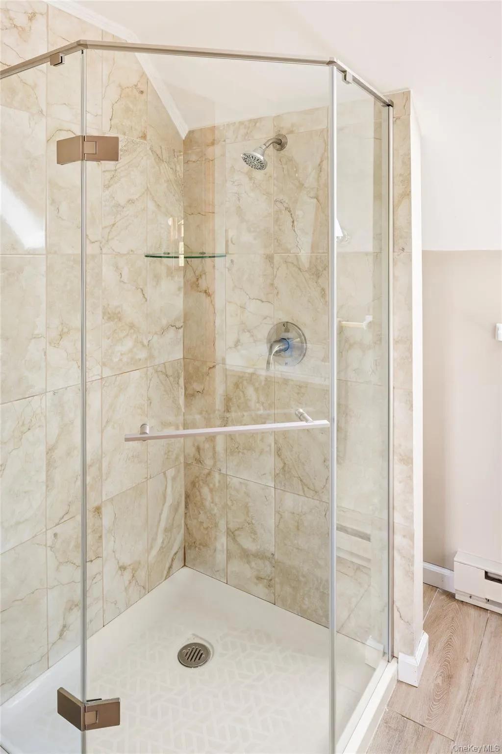 Bathroom with a shower stall, wood finished floors, crown molding, lofted ceiling, and a baseboard radiator Bathroom with a shower stall, wood finished floors, crown molding, lofted ceiling, and a baseboard radiator