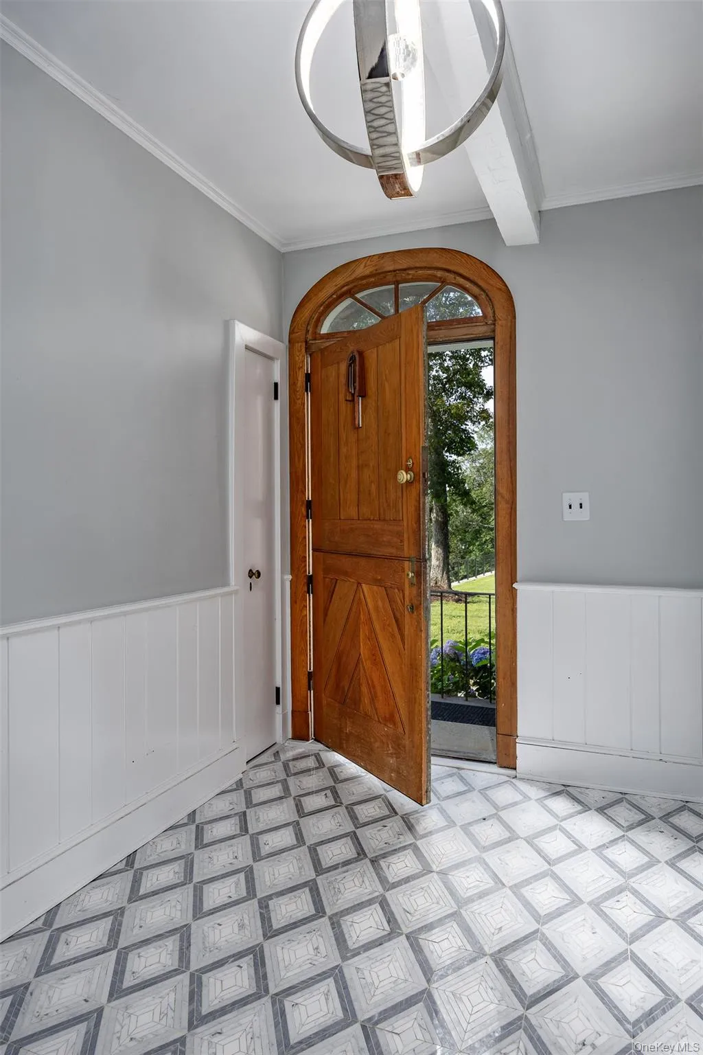 Foyer entrance with light flooring, wainscoting, and ornamental molding Foyer entrance with light flooring, wainscoting, and ornamental molding