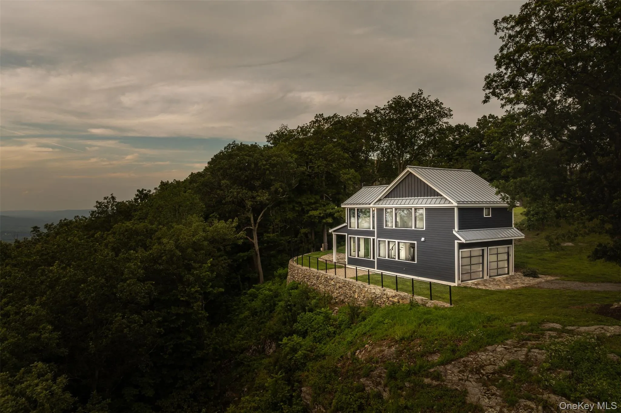 View of home's exterior featuring a metal roof, a standing seam roof, an attached garage, driveway, and a lawn View of home's exterior featuring a metal roof, a standing seam roof, an attached garage, driveway, and a lawn