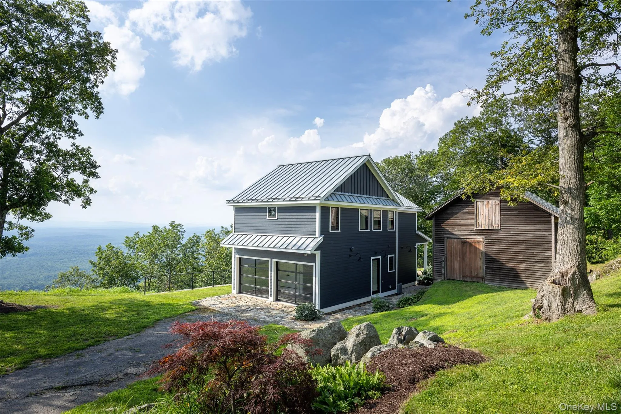 Rear view of property featuring a standing seam roof, a metal roof, asphalt driveway, a garage, and a yard Rear view of property featuring a standing seam roof, a metal roof, asphalt driveway, a garage, and a yard