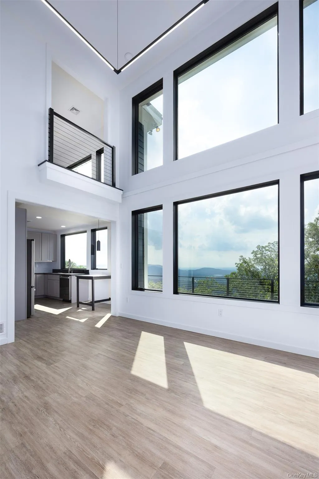 Unfurnished living room with a towering ceiling and light wood-type flooring Unfurnished living room with a towering ceiling and light wood-type flooring