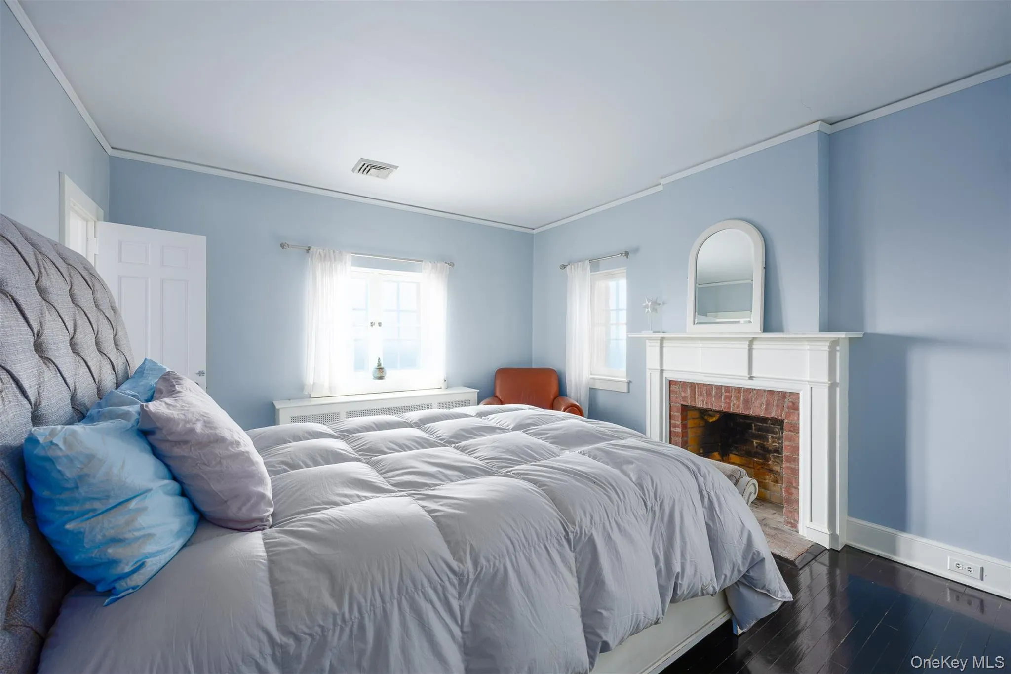 Bedroom featuring ornamental molding, dark wood finished floors, and a fireplace Bedroom featuring ornamental molding, dark wood finished floors, and a fireplace