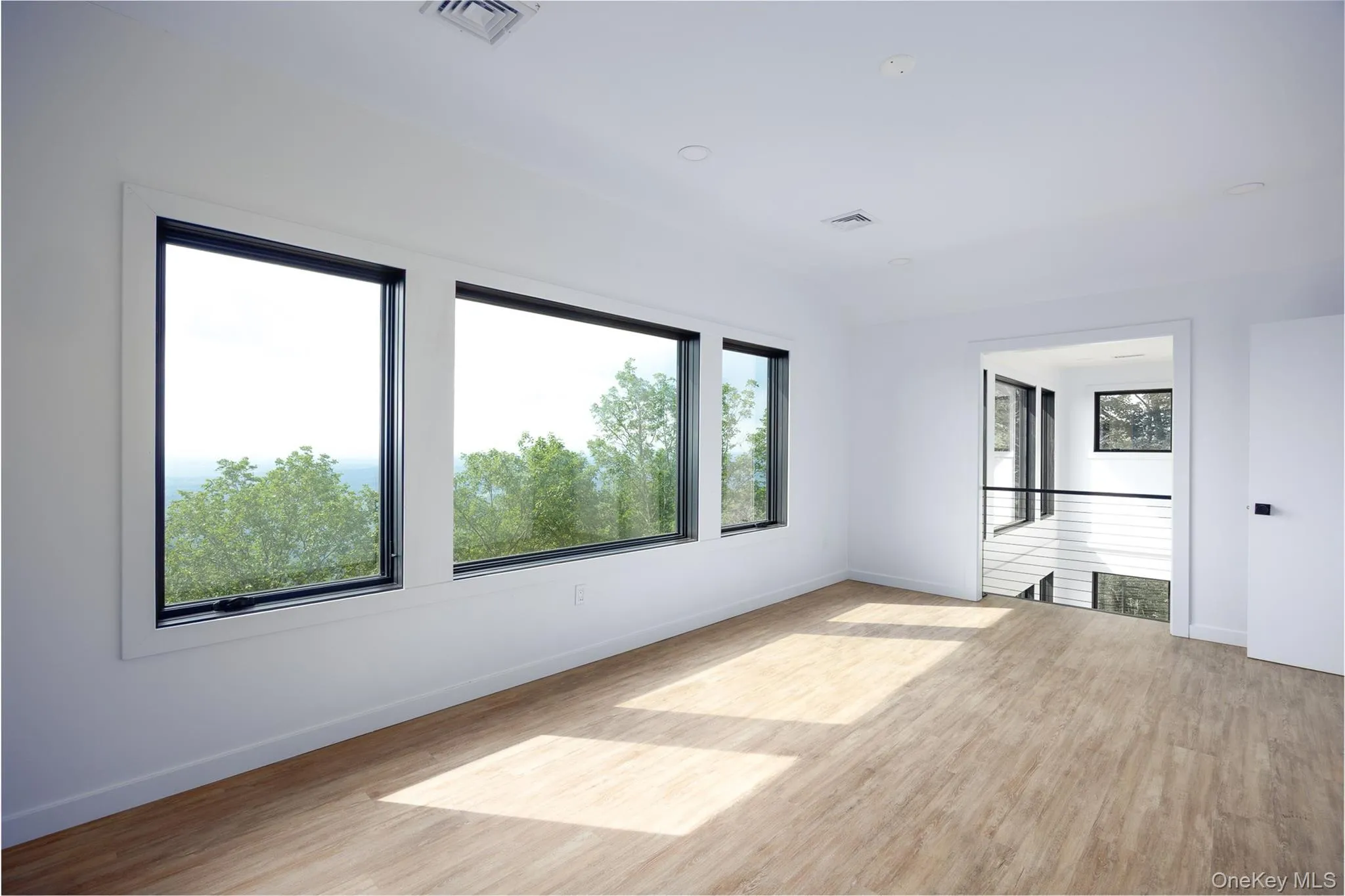 Spare room with plenty of natural light and wood finished floors Spare room with plenty of natural light and wood finished floors