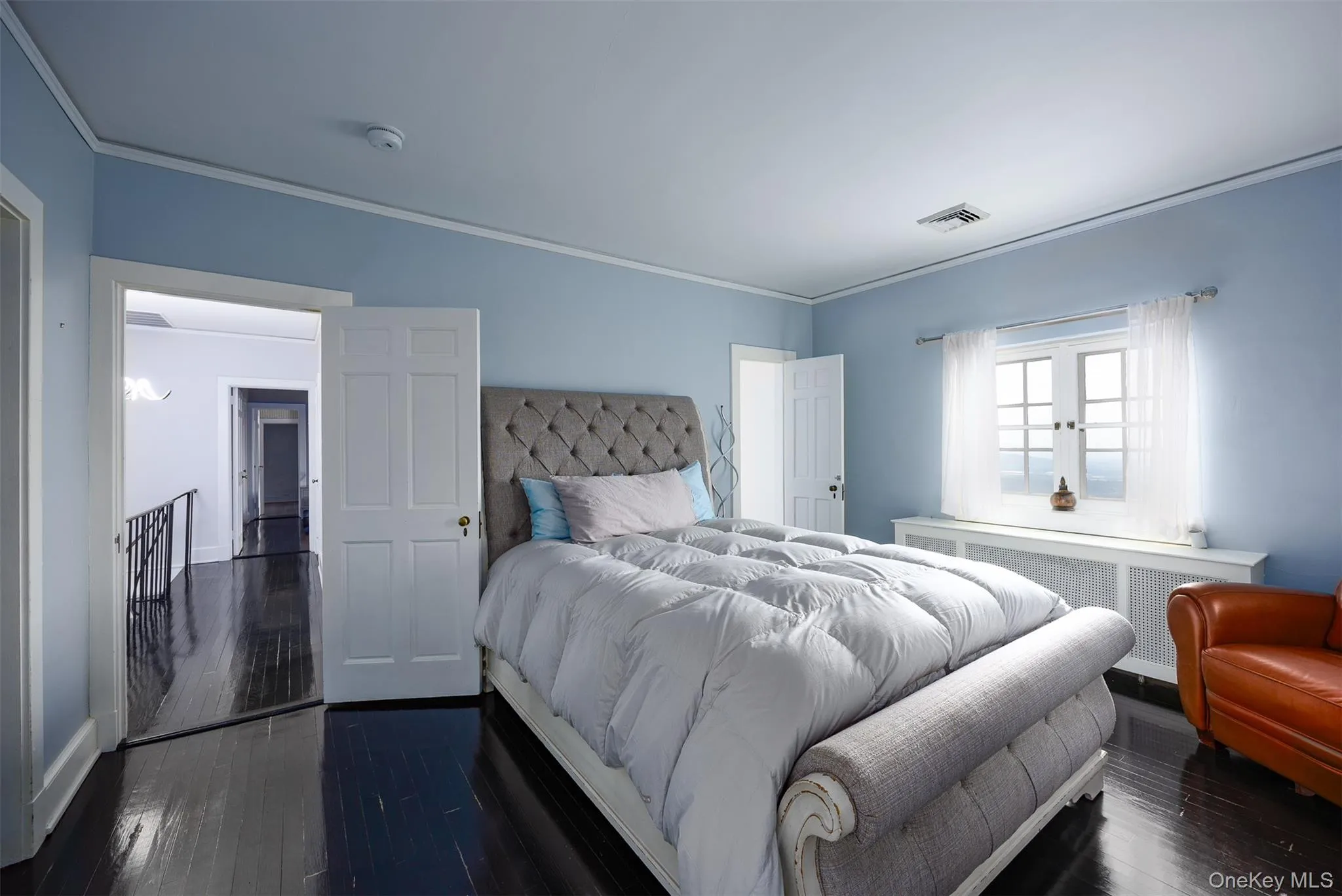 Bedroom featuring radiator heating unit, ornamental molding, and hardwood / wood-style floors Bedroom featuring radiator heating unit, ornamental molding, and hardwood / wood-style floors