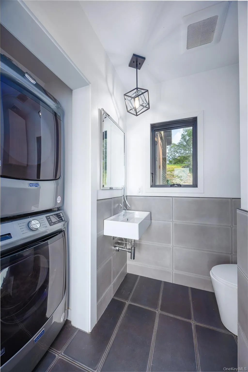 Half bathroom with stacked washer / dryer and wainscoting Half bathroom with stacked washer / dryer and wainscoting