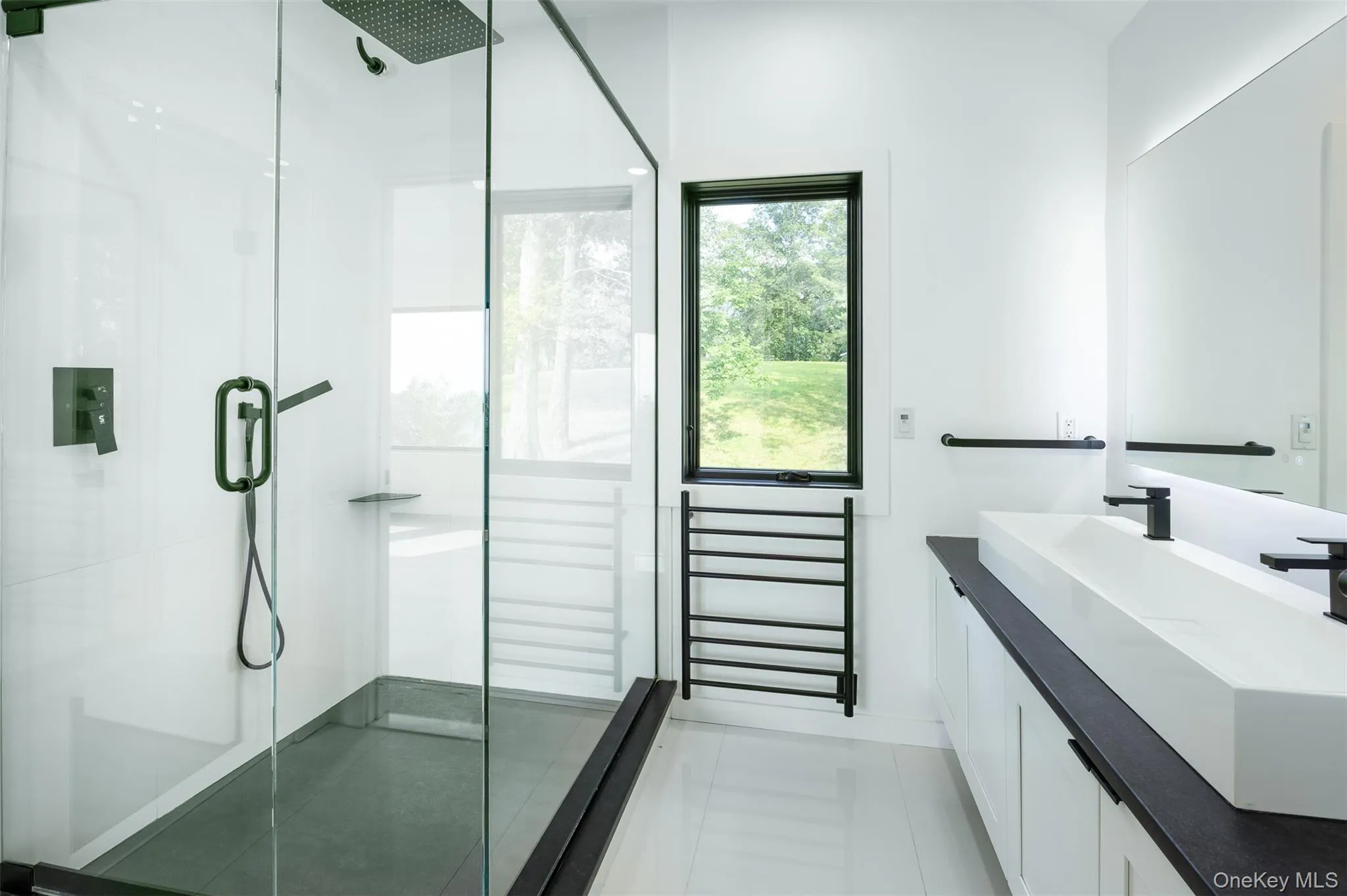 Full bathroom with a shower stall, vanity, and a towel warmer Full bathroom with a shower stall, vanity, and a towel warmer