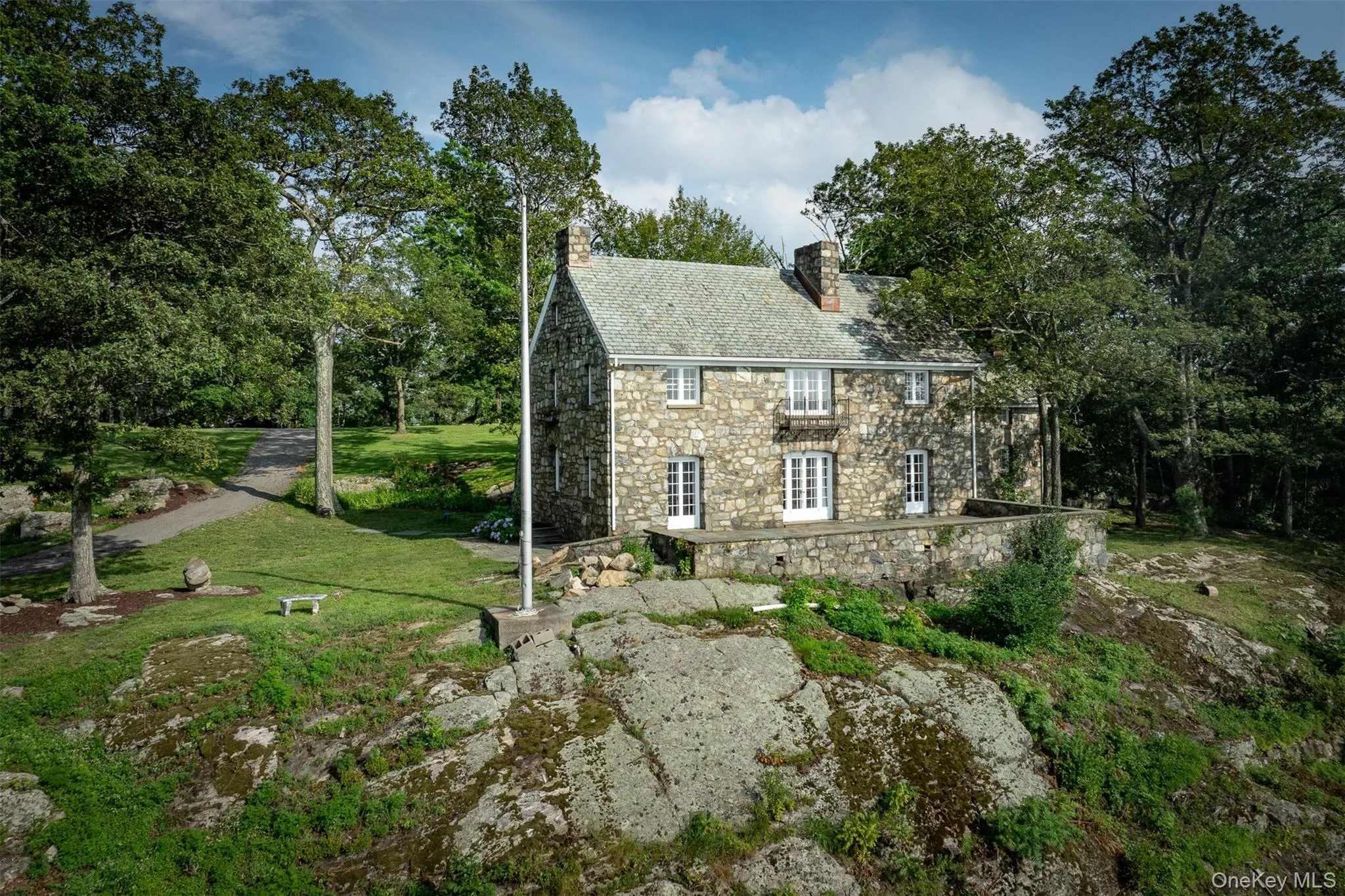 View of side of home featuring a high end roof, stone siding, a lawn, and a chimney View of side of home featuring a high end roof, stone siding, a lawn, and a chimney