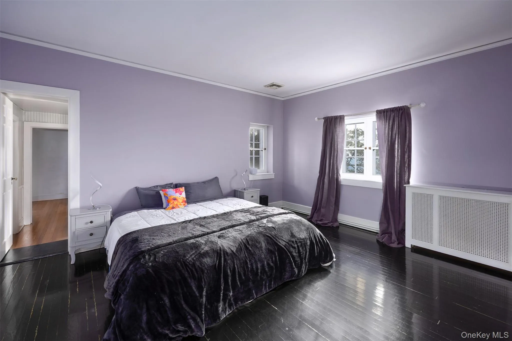 Bedroom with radiator heating unit, ornamental molding, and wood finished floors Bedroom with radiator heating unit, ornamental molding, and wood finished floors