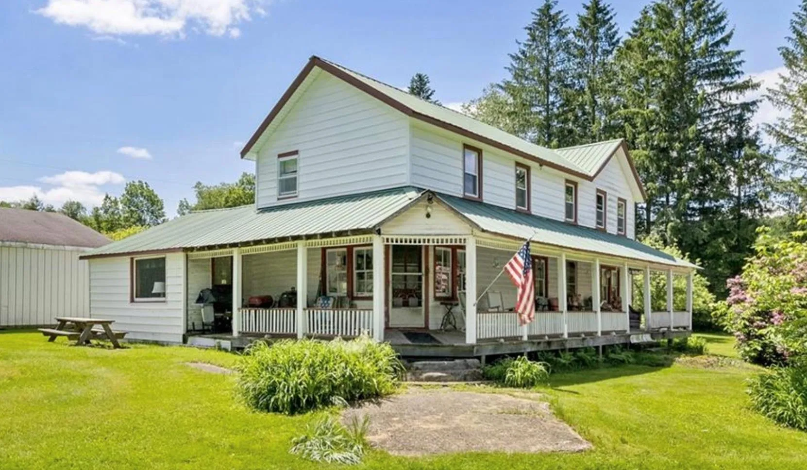 Back of house with a yard, a metal roof, and covered porch Back of house with a yard, a metal roof, and covered porch