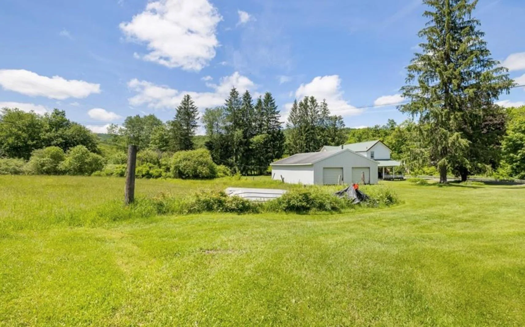 View of green lawn featuring an outdoor structure and view of wooded area View of green lawn featuring an outdoor structure and view of wooded area