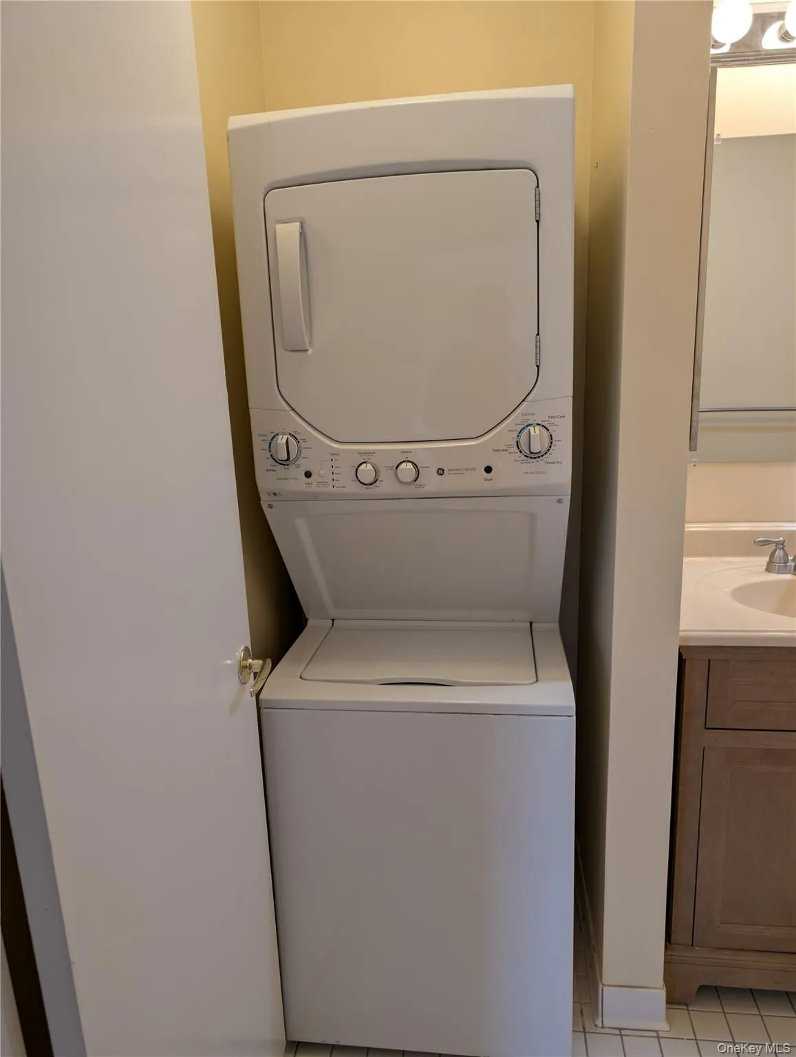 Laundry room with light tile patterned floors and stacked washer and clothes dryer Laundry room with light tile patterned floors and stacked washer and clothes dryer