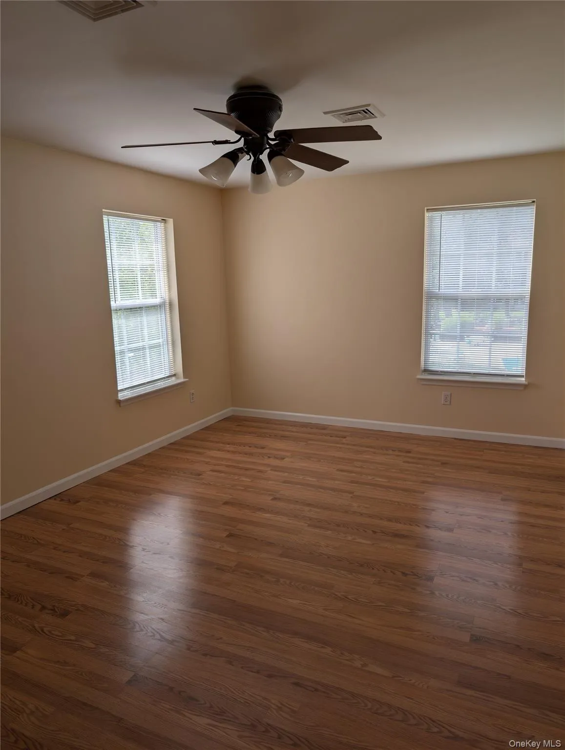 Primary bedroom with wood finished floors, a ceiling fan and windows on 2 sides. Primary bedroom with wood finished floors, a ceiling fan and windows on 2 sides.