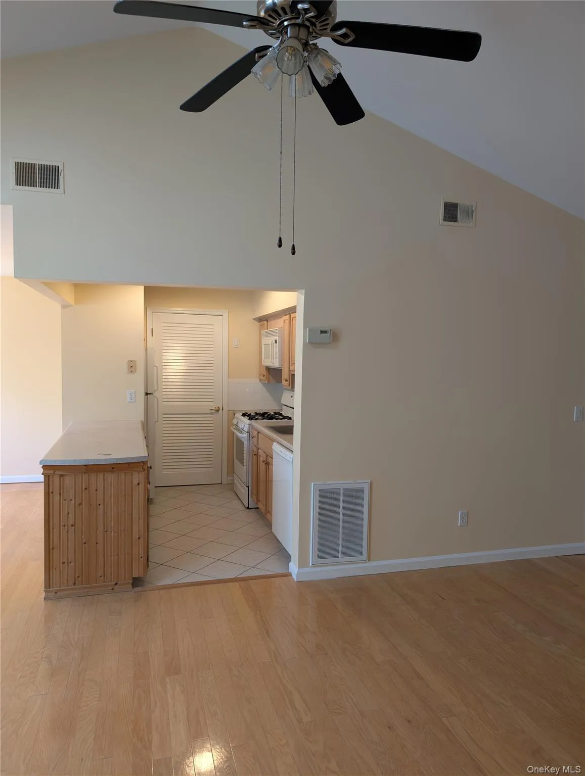 Kitchen featuring white appliances, light countertops, and a serving counter. Kitchen featuring white appliances, light countertops, and a serving counter.