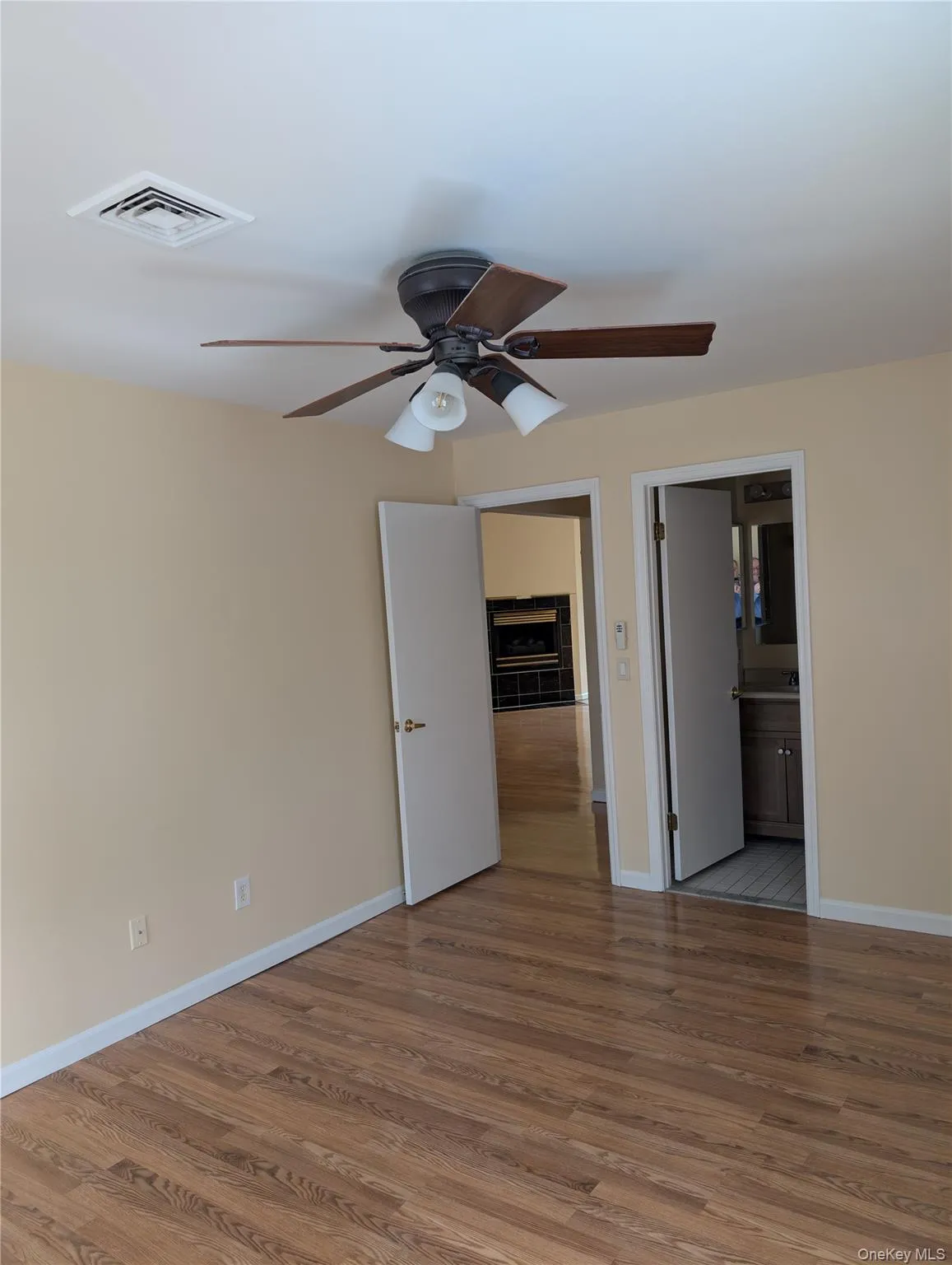 Primary bedroom with light wood-type flooring, a ceiling fan, and connected private bathroom Primary bedroom with light wood-type flooring, a ceiling fan, and connected private bathroom