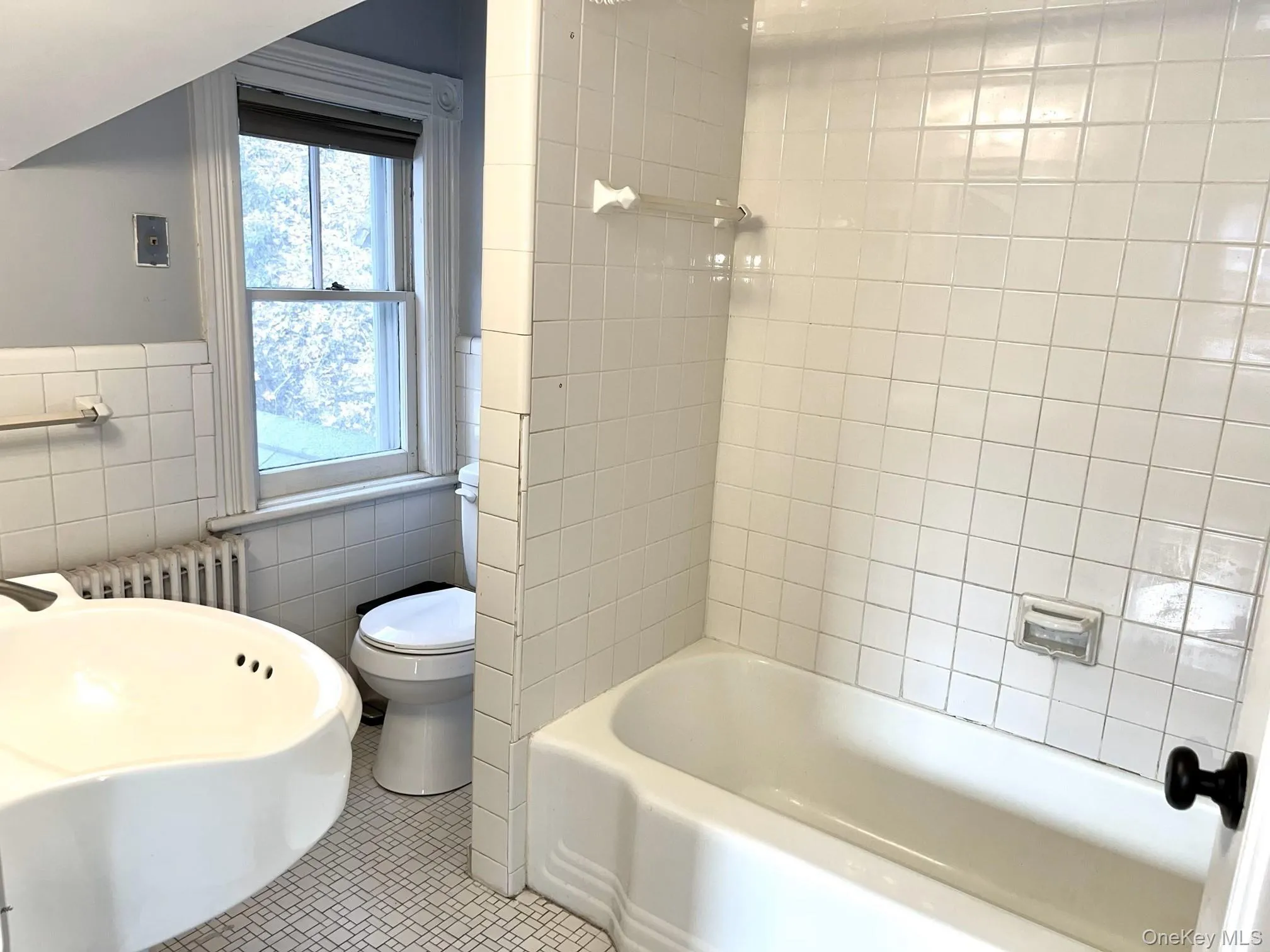 Full bathroom featuring tiled shower / bath, tile walls, radiator heating unit, and tile patterned flooring Full bathroom featuring tiled shower / bath, tile walls, radiator heating unit, and tile patterned flooring