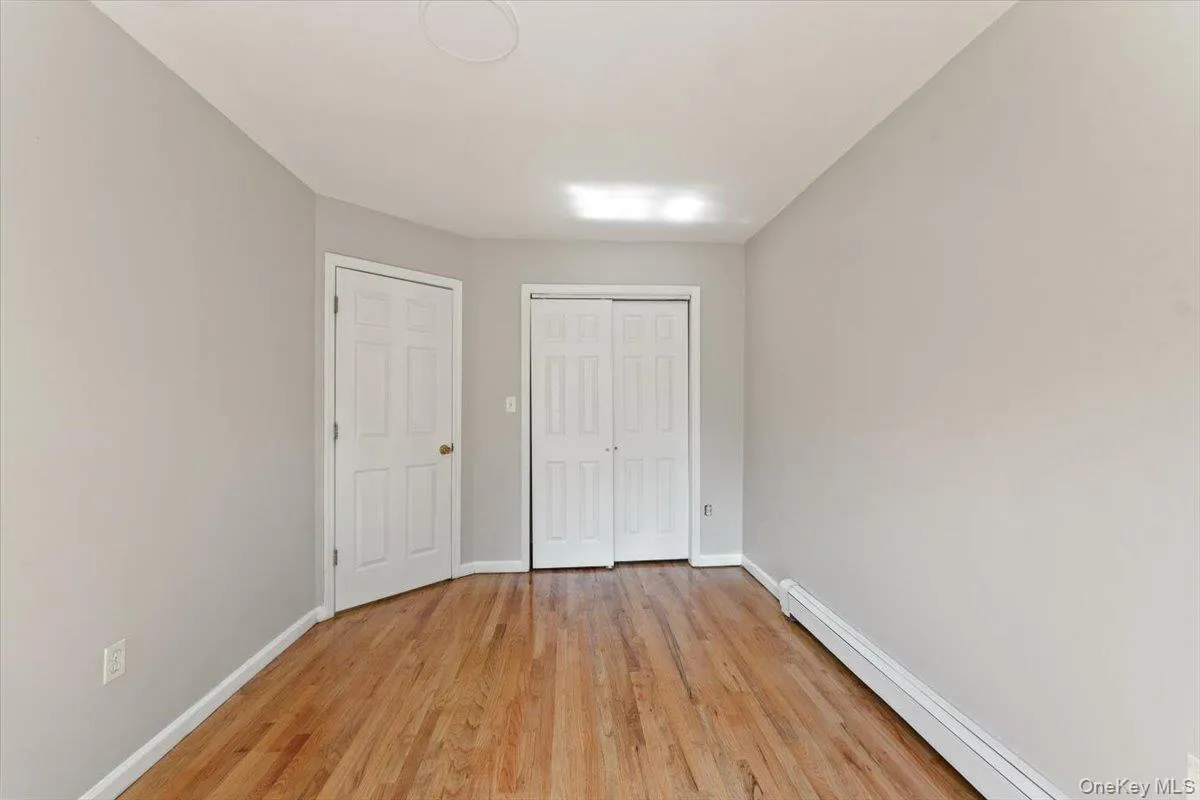 Unfurnished bedroom featuring a baseboard radiator, light wood-type flooring, and a closet Unfurnished bedroom featuring a baseboard radiator, light wood-type flooring, and a closet