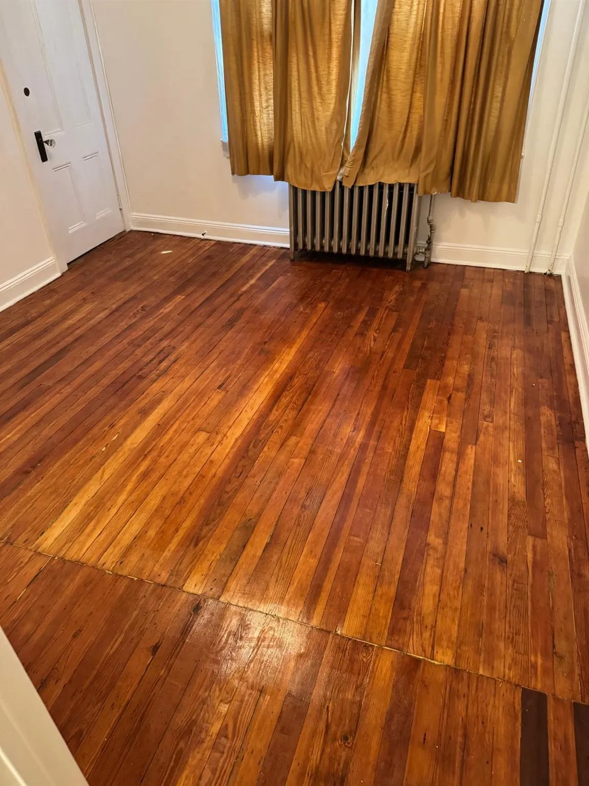 Spare room featuring radiator and dark wood finished floors Spare room featuring radiator and dark wood finished floors