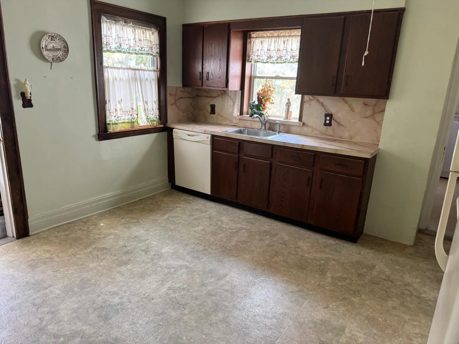 Kitchen with dishwasher, light countertops, backsplash, and dark brown cabinets Kitchen with dishwasher, light countertops, backsplash, and dark brown cabinets