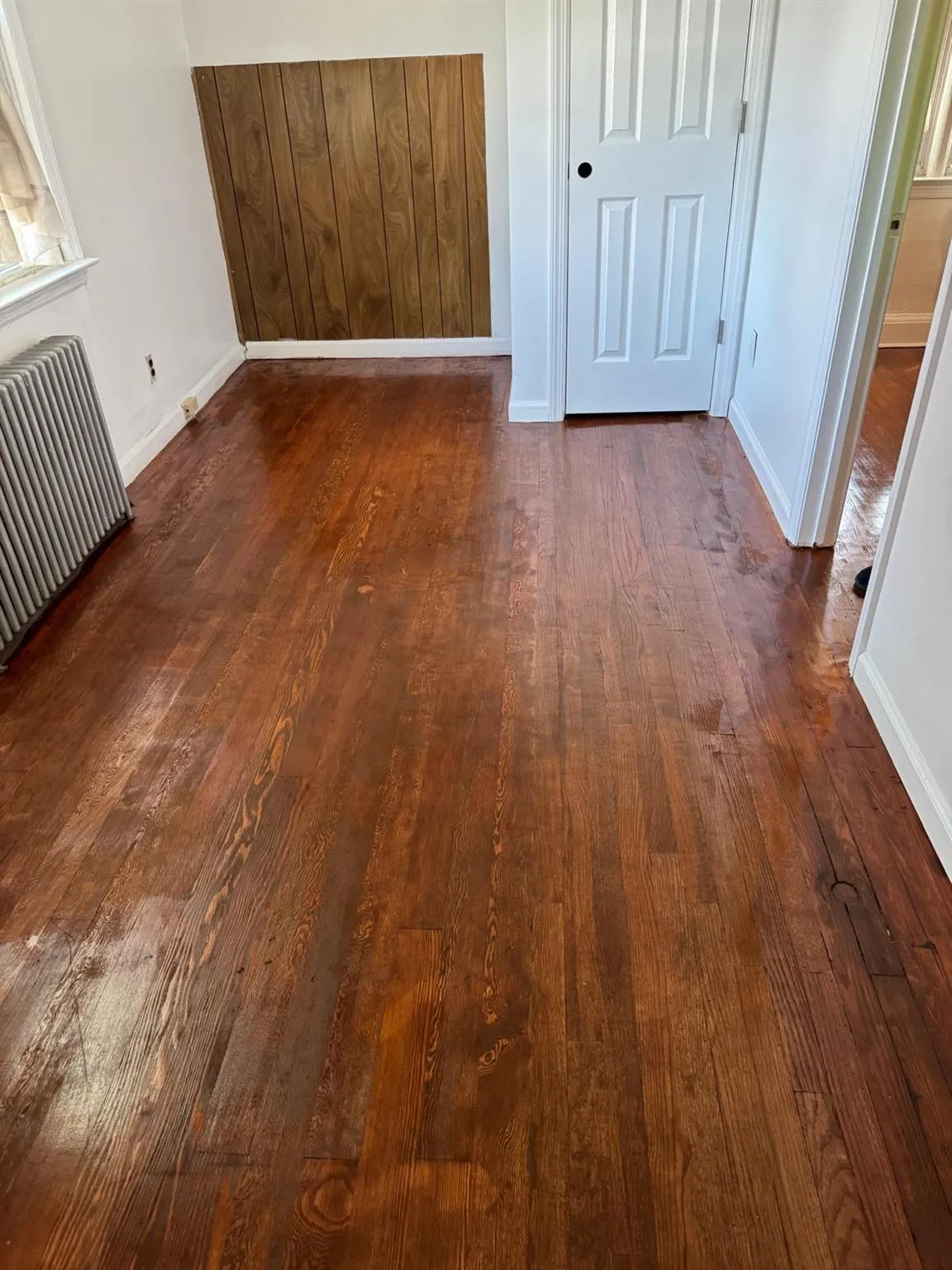 Unfurnished bedroom with radiator and dark wood finished floors Unfurnished bedroom with radiator and dark wood finished floors