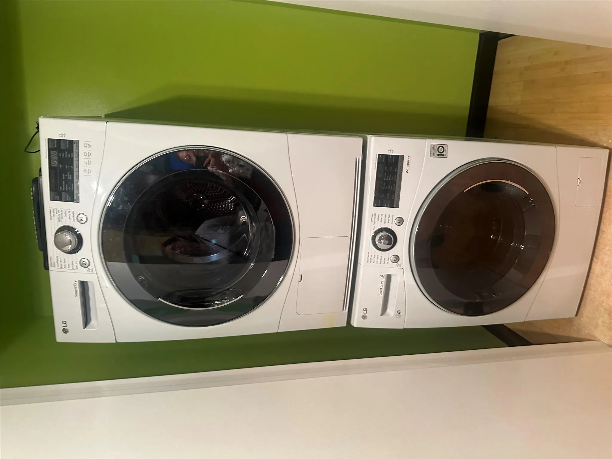 Laundry area featuring stacked washer and clothes dryer and wood finished floors Laundry area featuring stacked washer and clothes dryer and wood finished floors