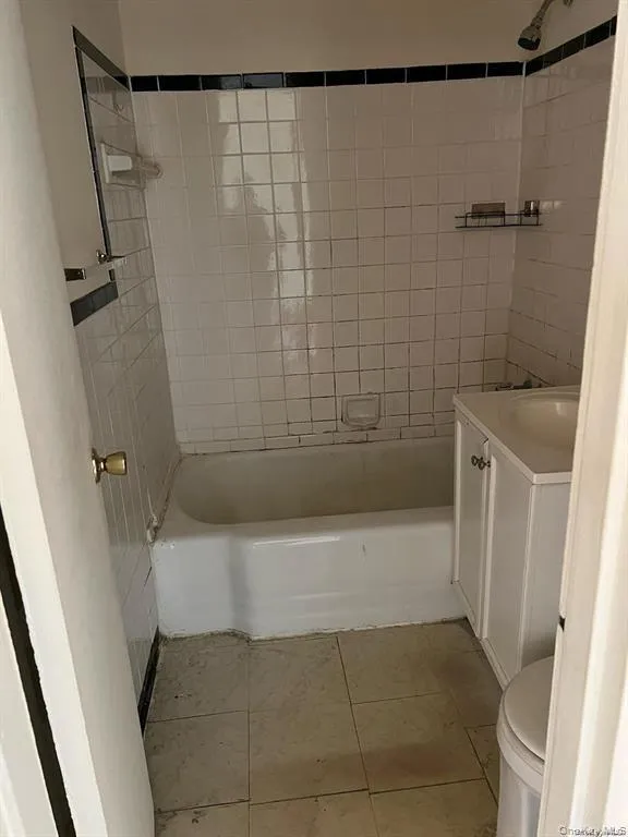 Full bathroom with toilet, vanity, tile patterned floors, and tiled shower / bath Full bathroom with toilet, vanity, tile patterned floors, and tiled shower / bath