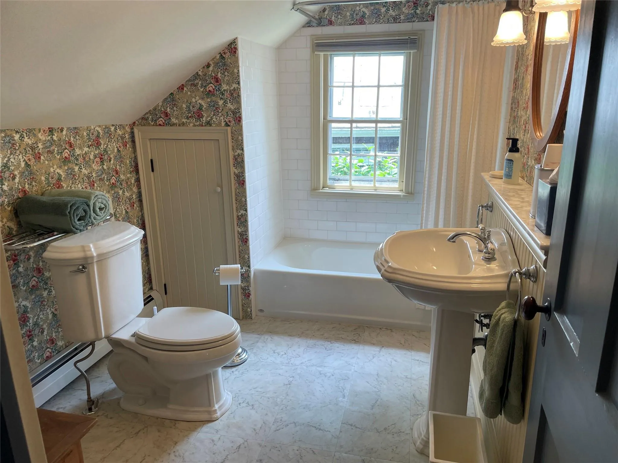 Bathroom featuring wallpapered walls, vaulted ceiling, a baseboard heating unit, and bathing tub / shower combination Bathroom featuring wallpapered walls, vaulted ceiling, a baseboard heating unit, and bathing tub / shower combination