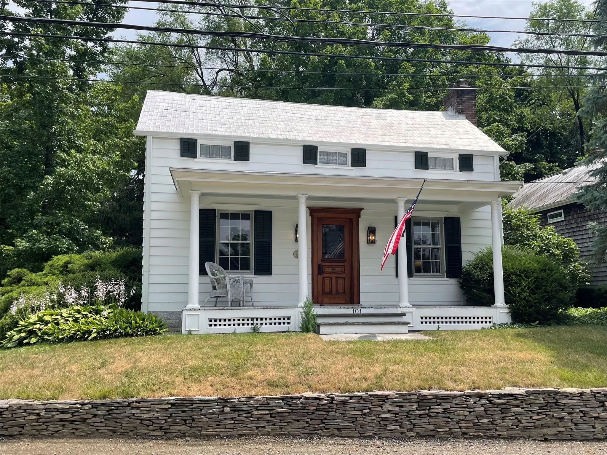 View of front facade featuring a porch, a chimney, and a front lawn View of front facade featuring a porch, a chimney, and a front lawn