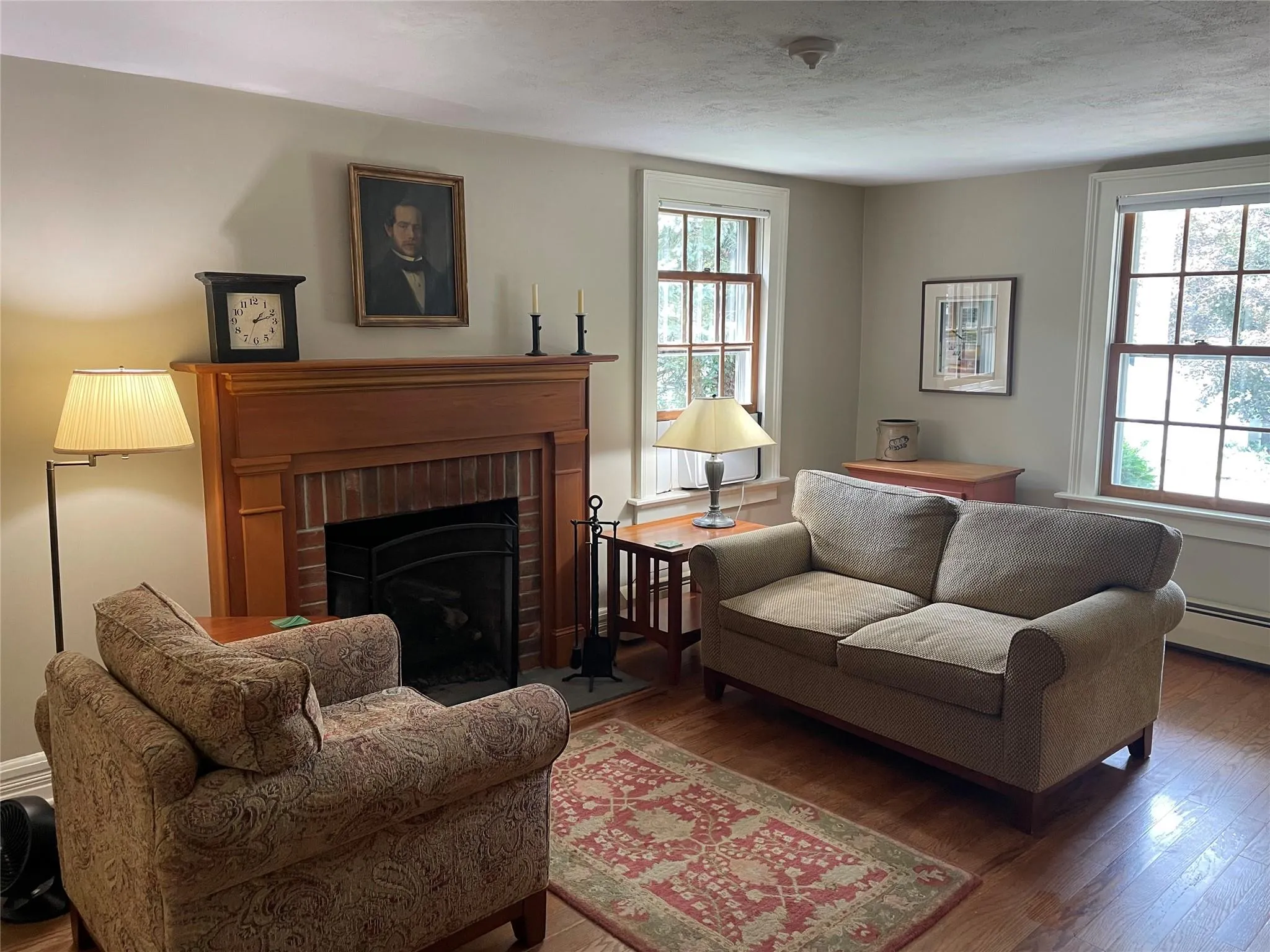 Living area with plenty of natural light, wood finished floors, and a brick fireplace Living area with plenty of natural light, wood finished floors, and a brick fireplace