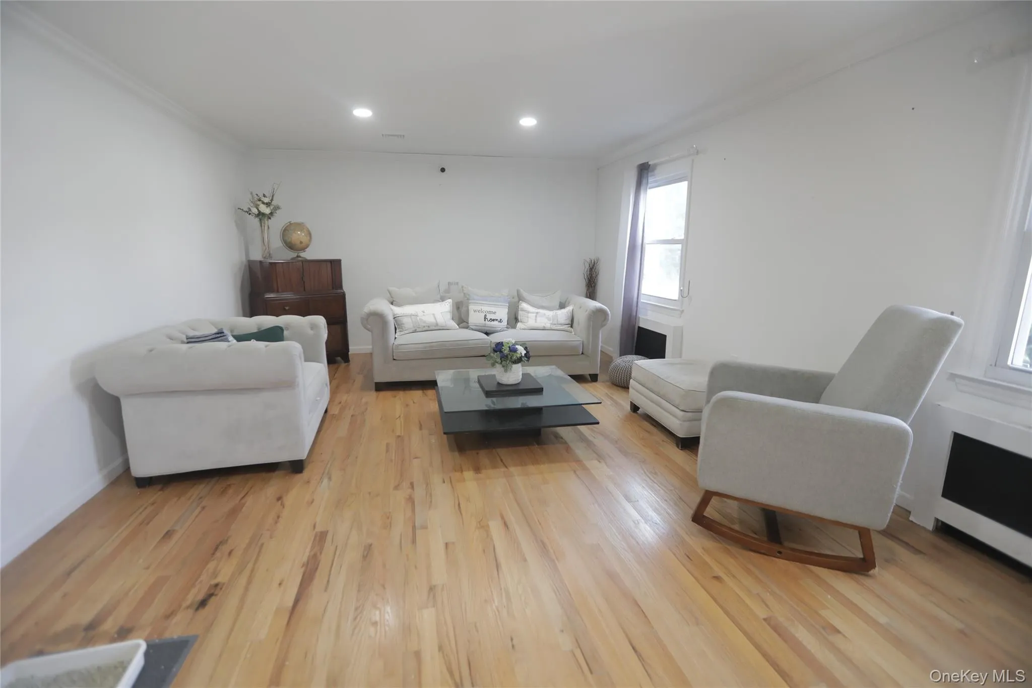 Living room featuring ornamental molding, light wood-type flooring, radiator, and recessed lighting Living room featuring ornamental molding, light wood-type flooring, radiator, and recessed lighting