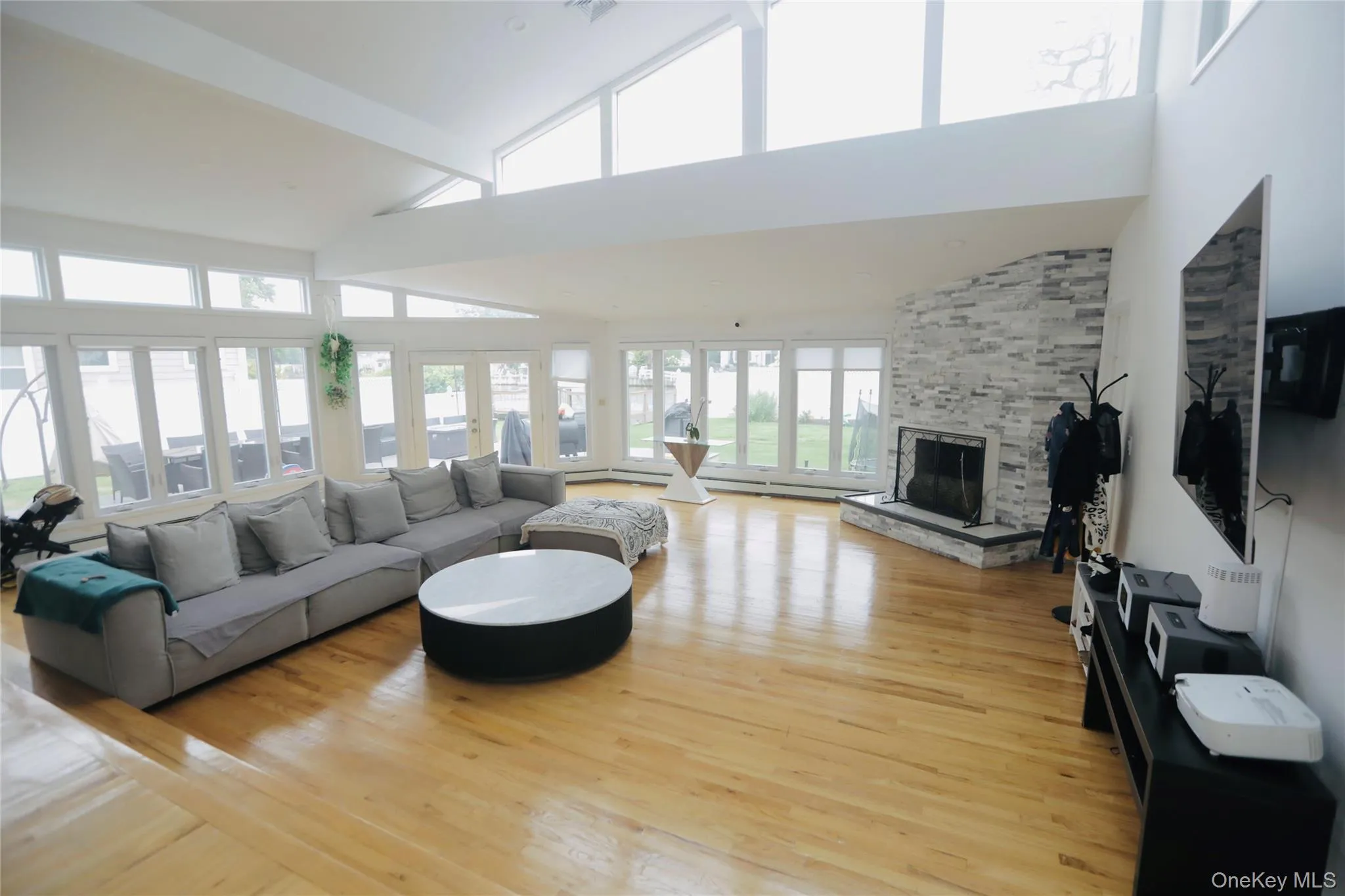 Living room featuring high vaulted ceiling, light wood-style floors, and a fireplace Living room featuring high vaulted ceiling, light wood-style floors, and a fireplace