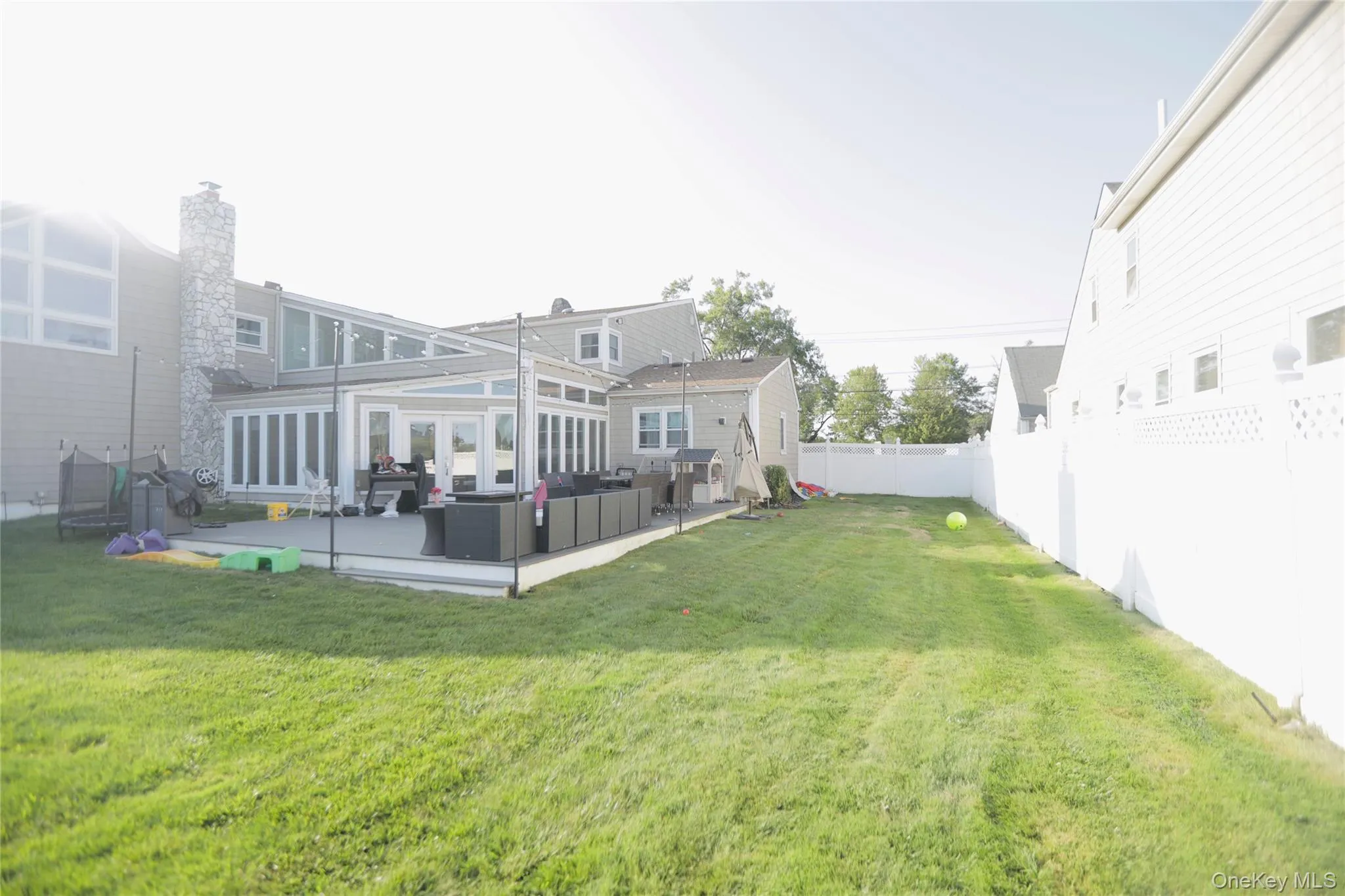 Fenced backyard with outdoor lounge area, a trampoline, and a deck Fenced backyard with outdoor lounge area, a trampoline, and a deck
