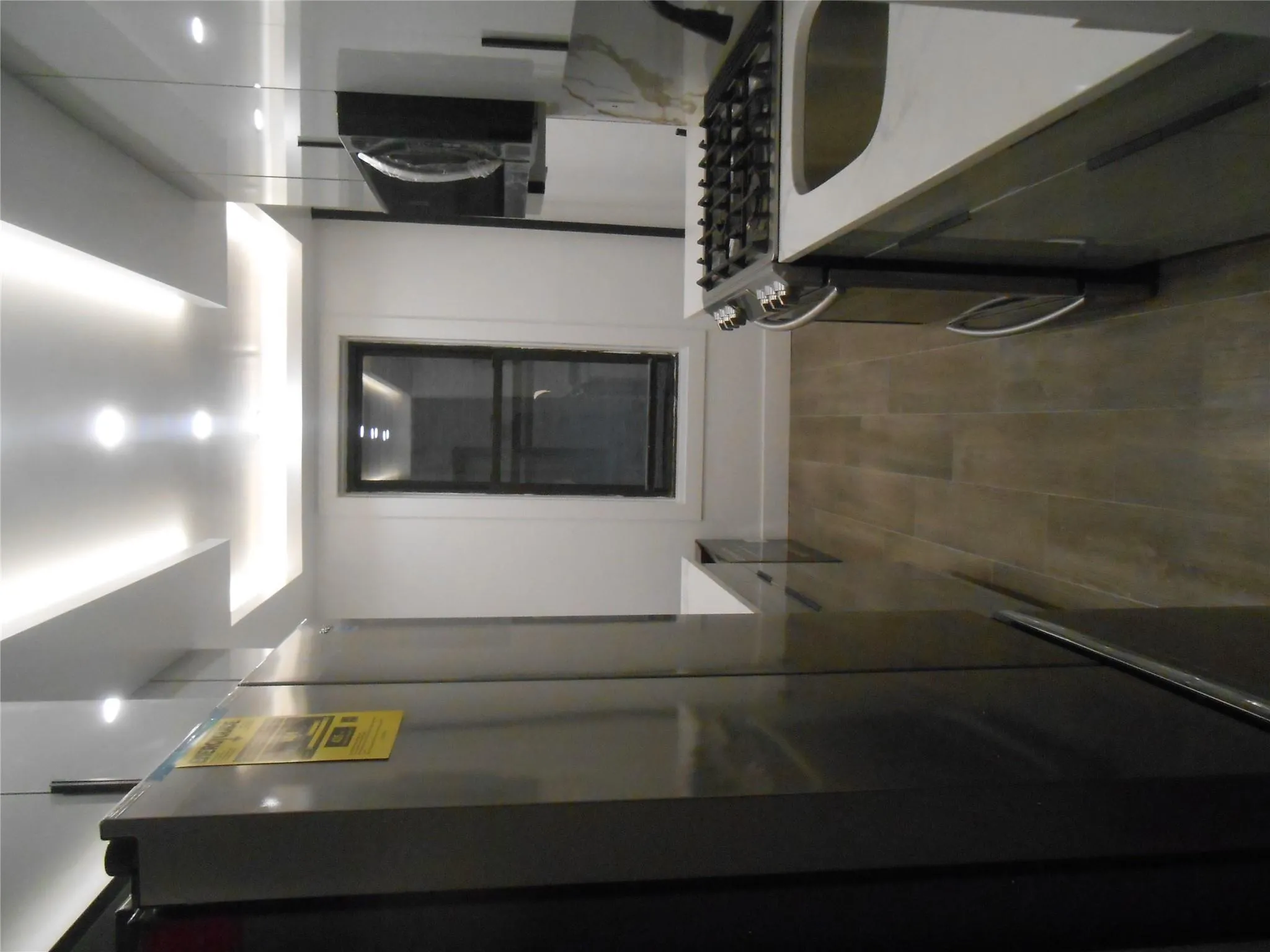 Kitchen with fridge, modern cabinets, stove, dark wood finished floors, and recessed lighting Kitchen with fridge, modern cabinets, stove, dark wood finished floors, and recessed lighting