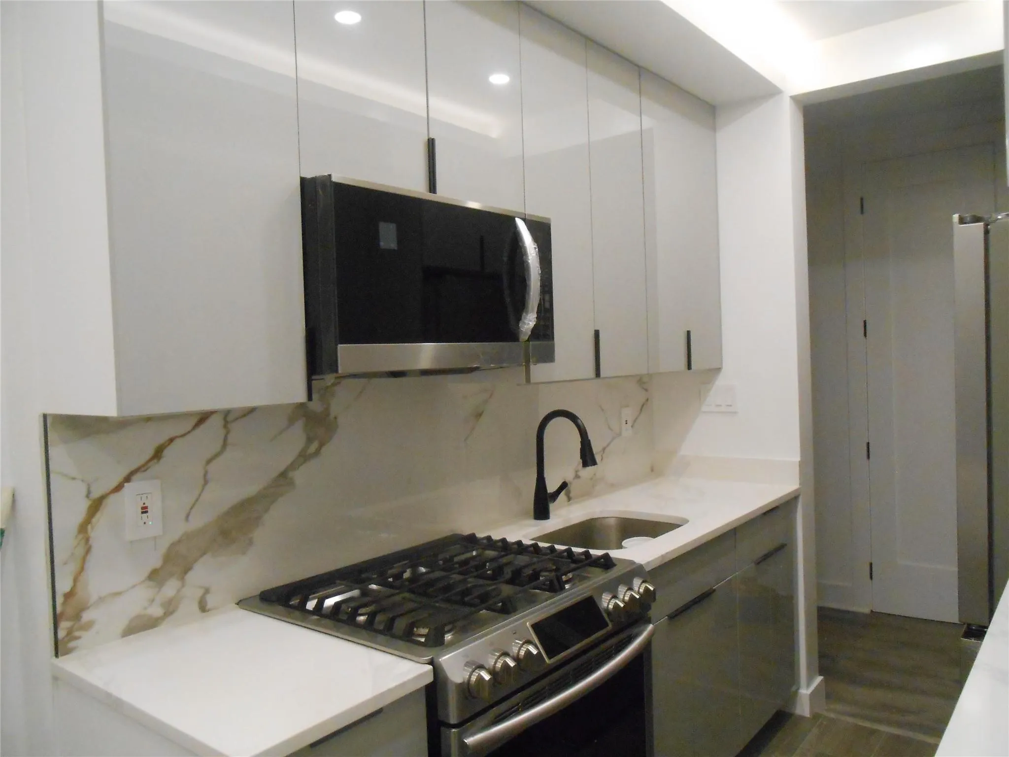 Kitchen with gas stove, white cabinets, backsplash, recessed lighting, and dark wood-style floors Kitchen with gas stove, white cabinets, backsplash, recessed lighting, and dark wood-style floors