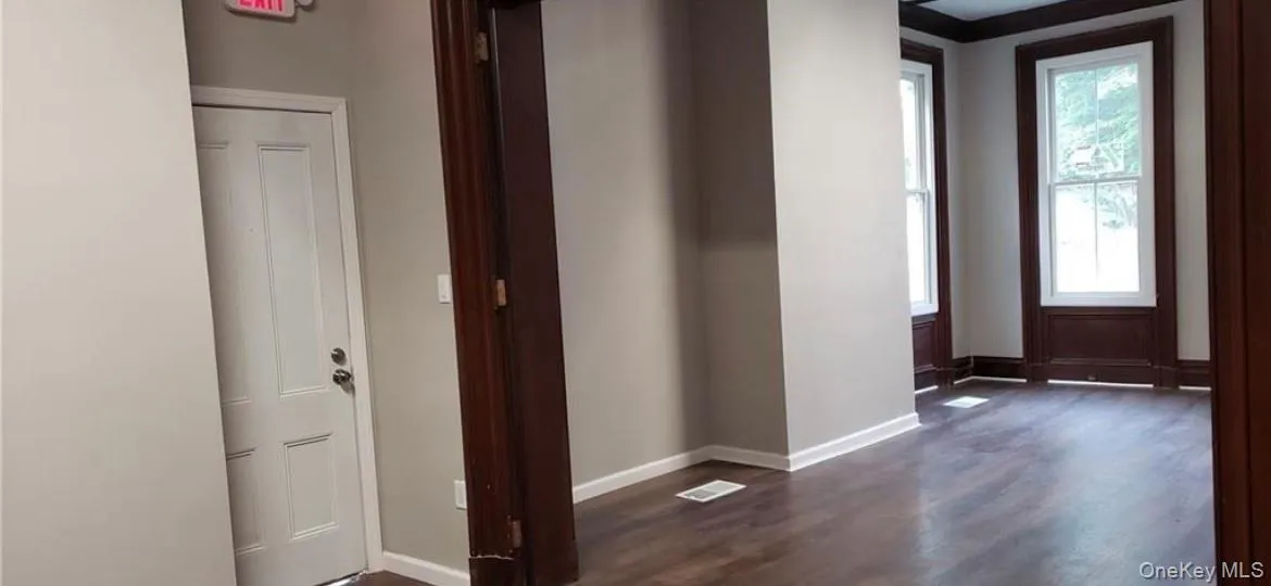 Hallway with dark hardwood / wood-style flooring and ornamental molding Hallway with dark hardwood / wood-style flooring and ornamental molding