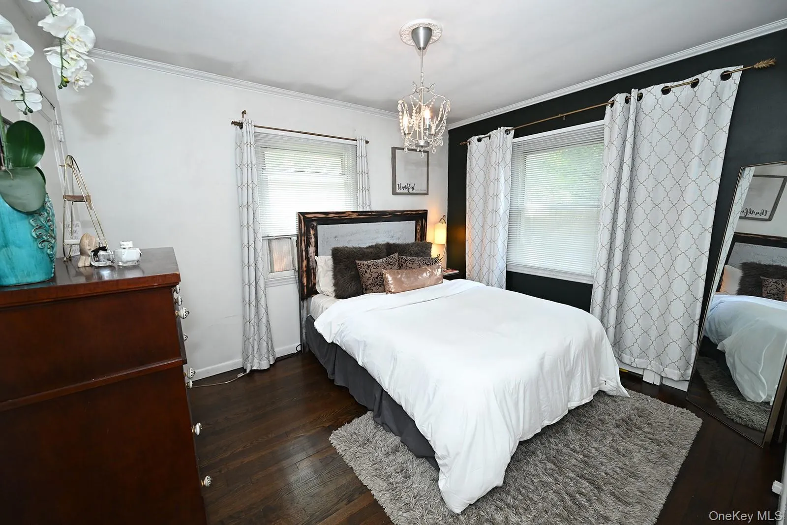 Bedroom with multiple windows, crown molding, wood-type flooring, and a chandelier Bedroom with multiple windows, crown molding, wood-type flooring, and a chandelier