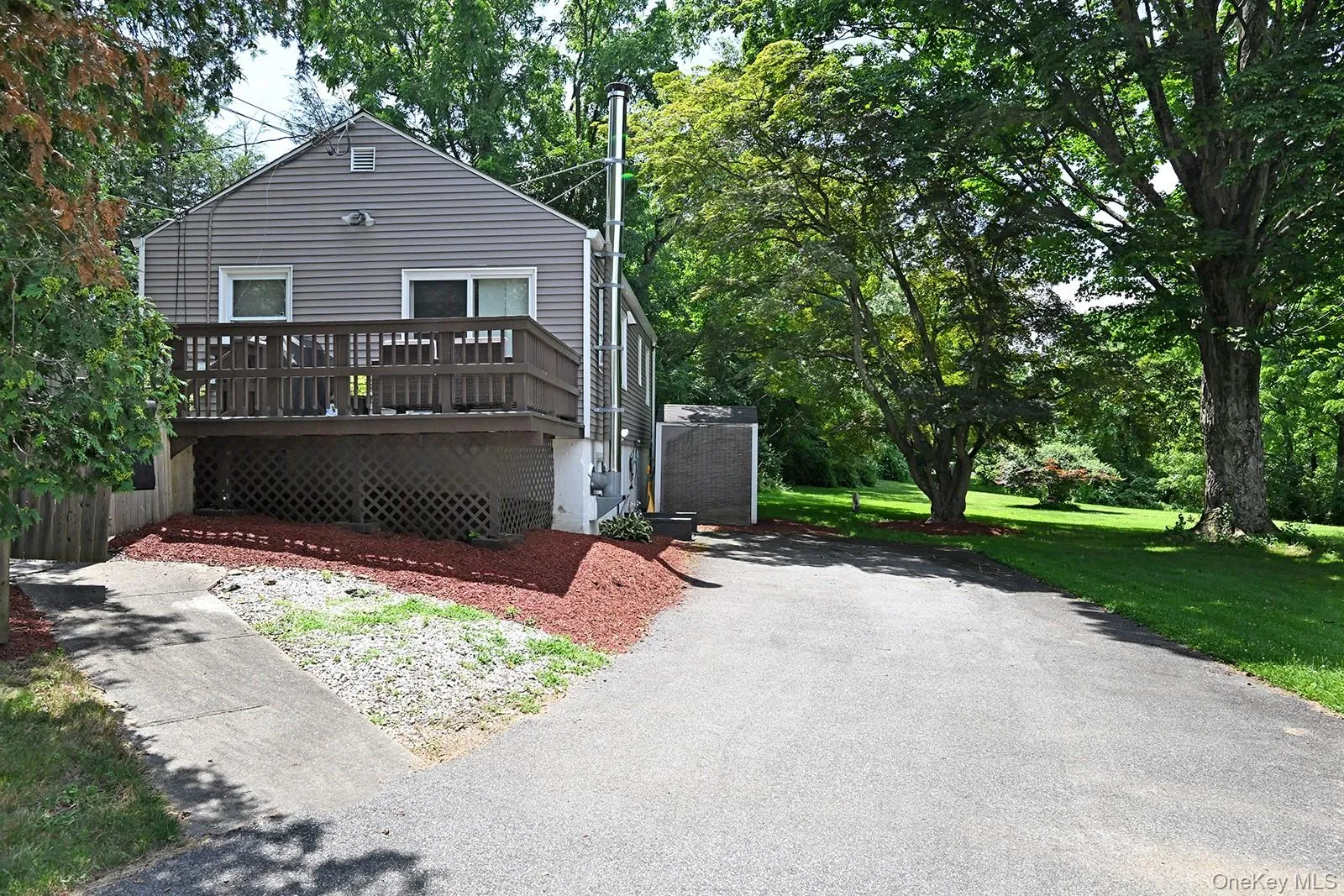 View of front facade with a deck, a front lawn, and asphalt driveway View of front facade with a deck, a front lawn, and asphalt driveway