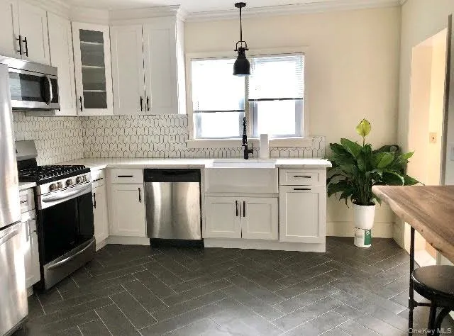 Kitchen featuring appliances with stainless steel finishes, light countertops, white cabinetry and molding Kitchen featuring appliances with stainless steel finishes, light countertops, white cabinetry and molding