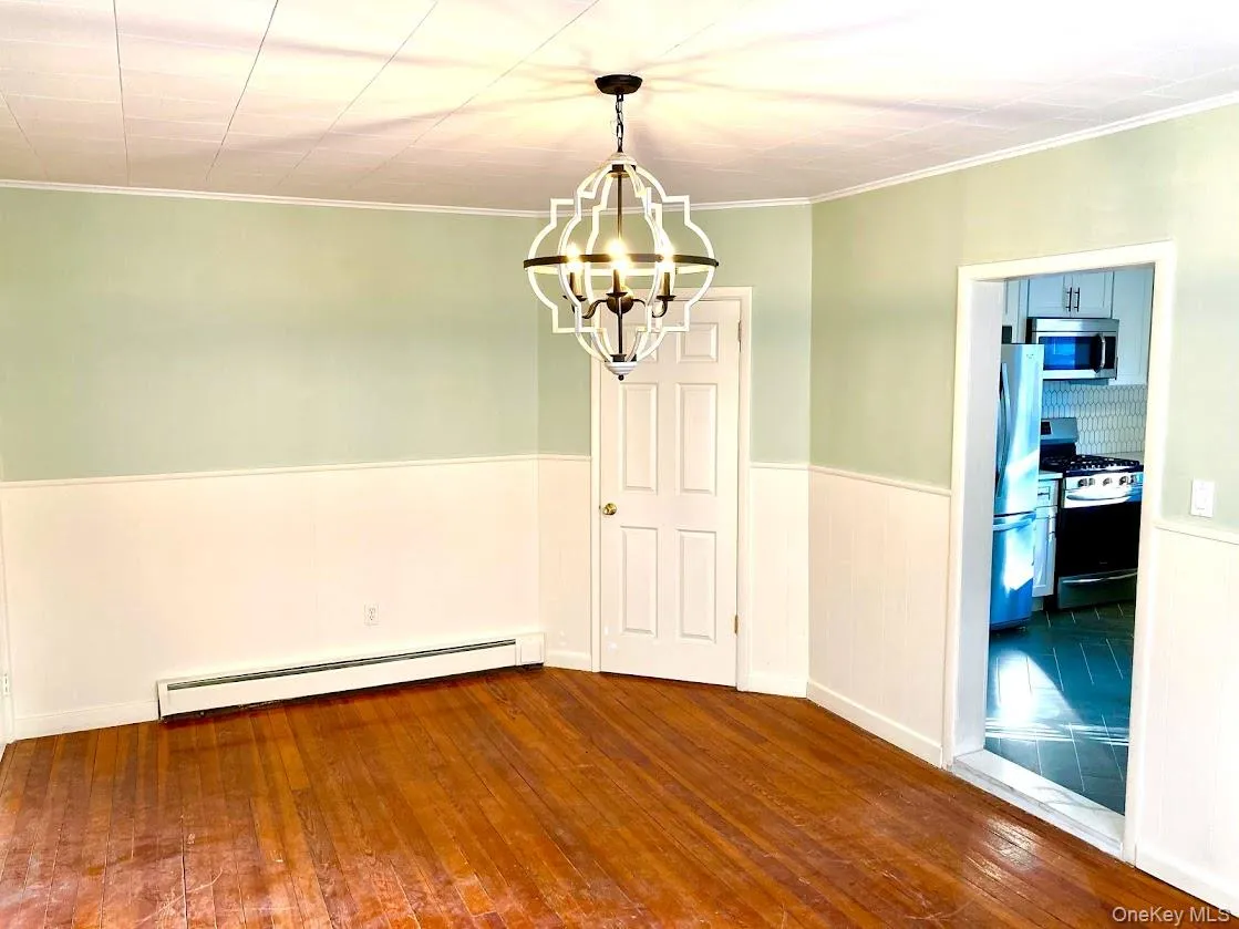 Dining room with chandelier, hardwood flooring, wainscoting paneling and molding Dining room with chandelier, hardwood flooring, wainscoting paneling and molding